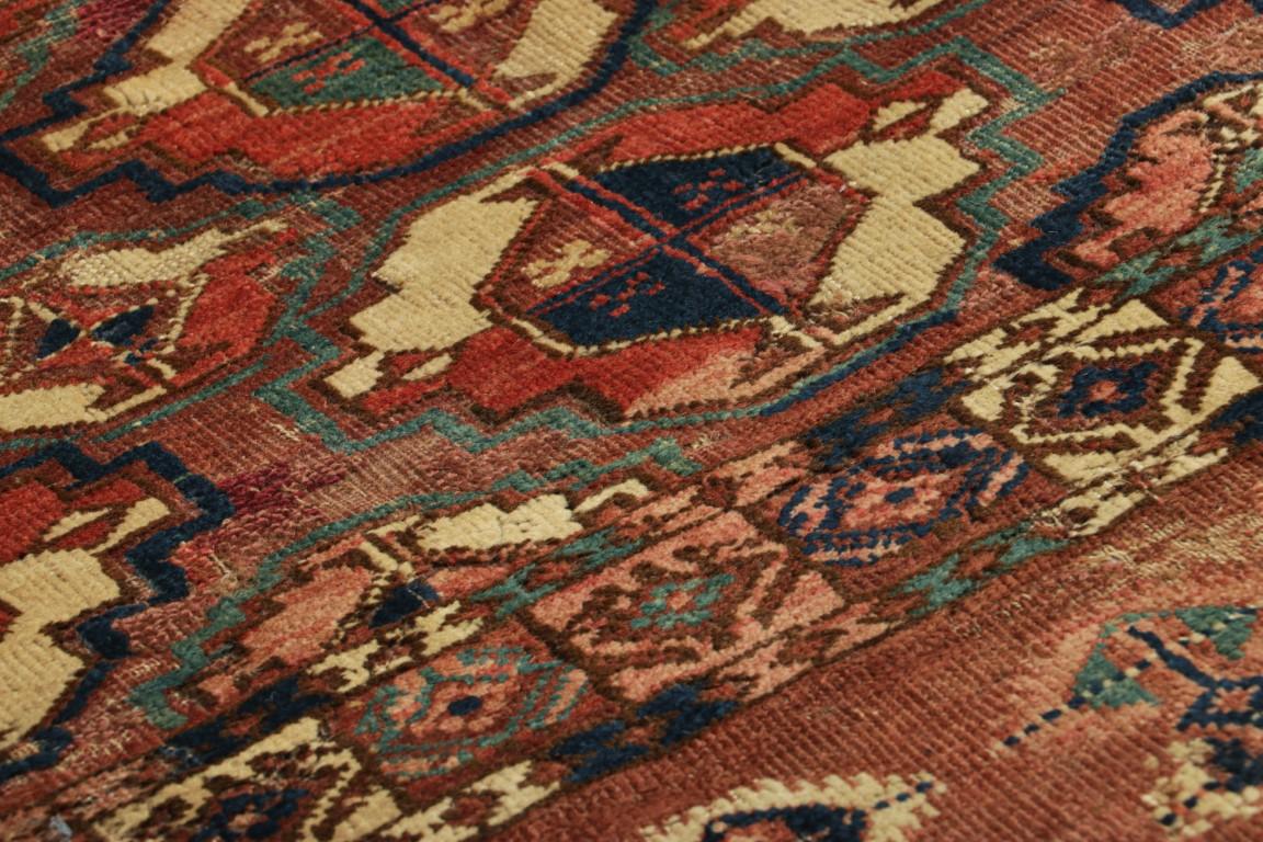 Realizzato con lana tessuta a mano, questo antico tessuto persiano Tekke 2x3 con nove medaglioni gül in rosso e beige su un ricco campo rosso rossastro, originario della Persia intorno al 1900-1910, è uno degli stili più collezionabili della nostra