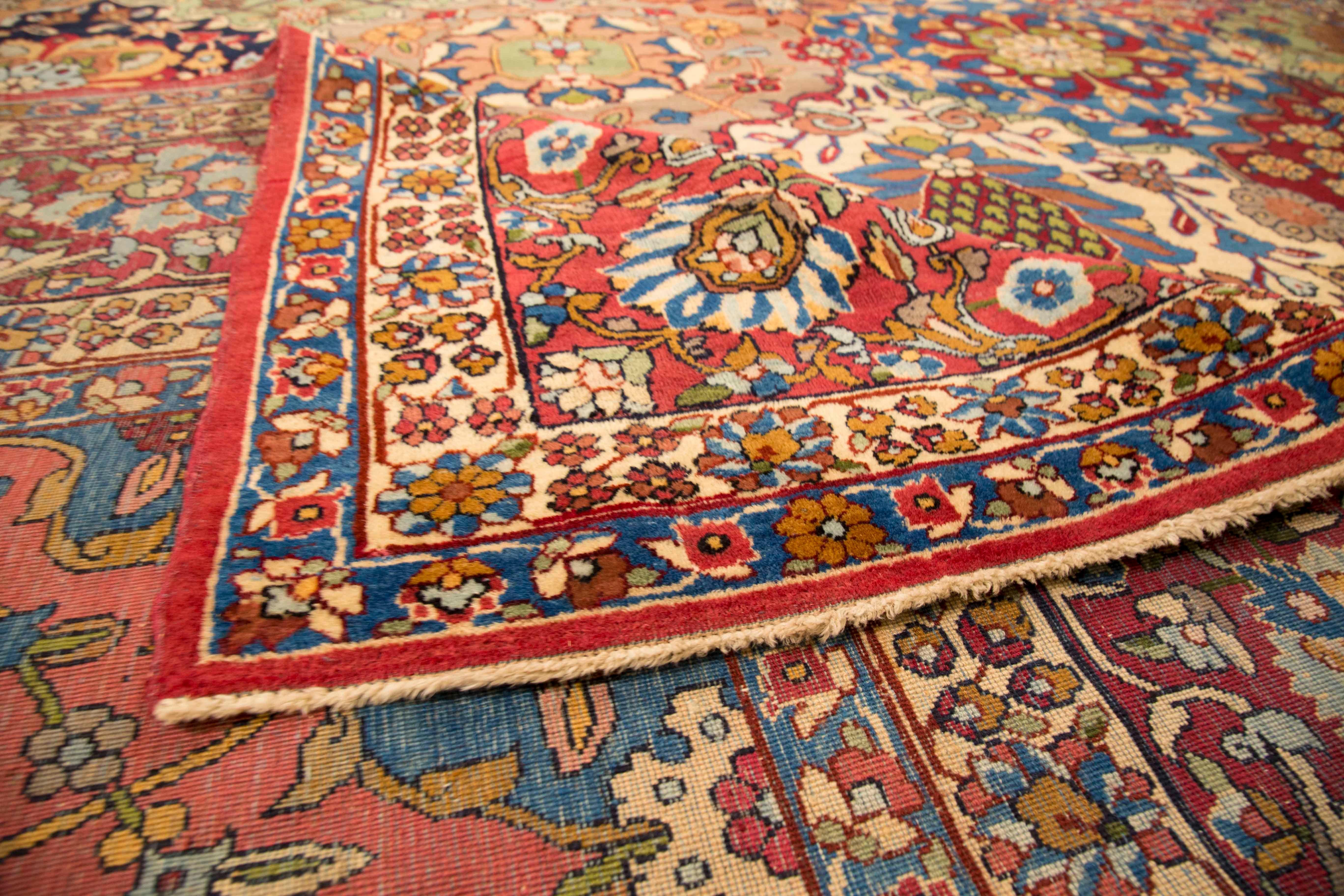 Antique Persian rug made in the 1920s. It’s handmade from fine, exquisite wool and colored with rich organic vegetable dyes. It features an open field design with multicolored flower bouquet patterns. This antique Persian rug has borders that are