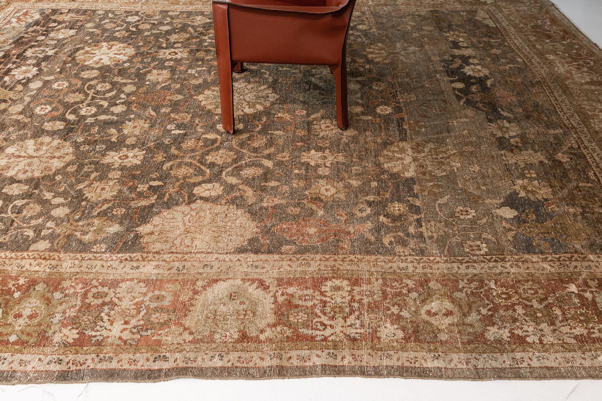 Displaying warm earth-tone colours with its relaxing intricacy, this Antique Persian Ziegler rug beautifully embodies a modern rustic style. The weathered abrashed mocha field is covered with an all-over Herati pattern and an array of blooming