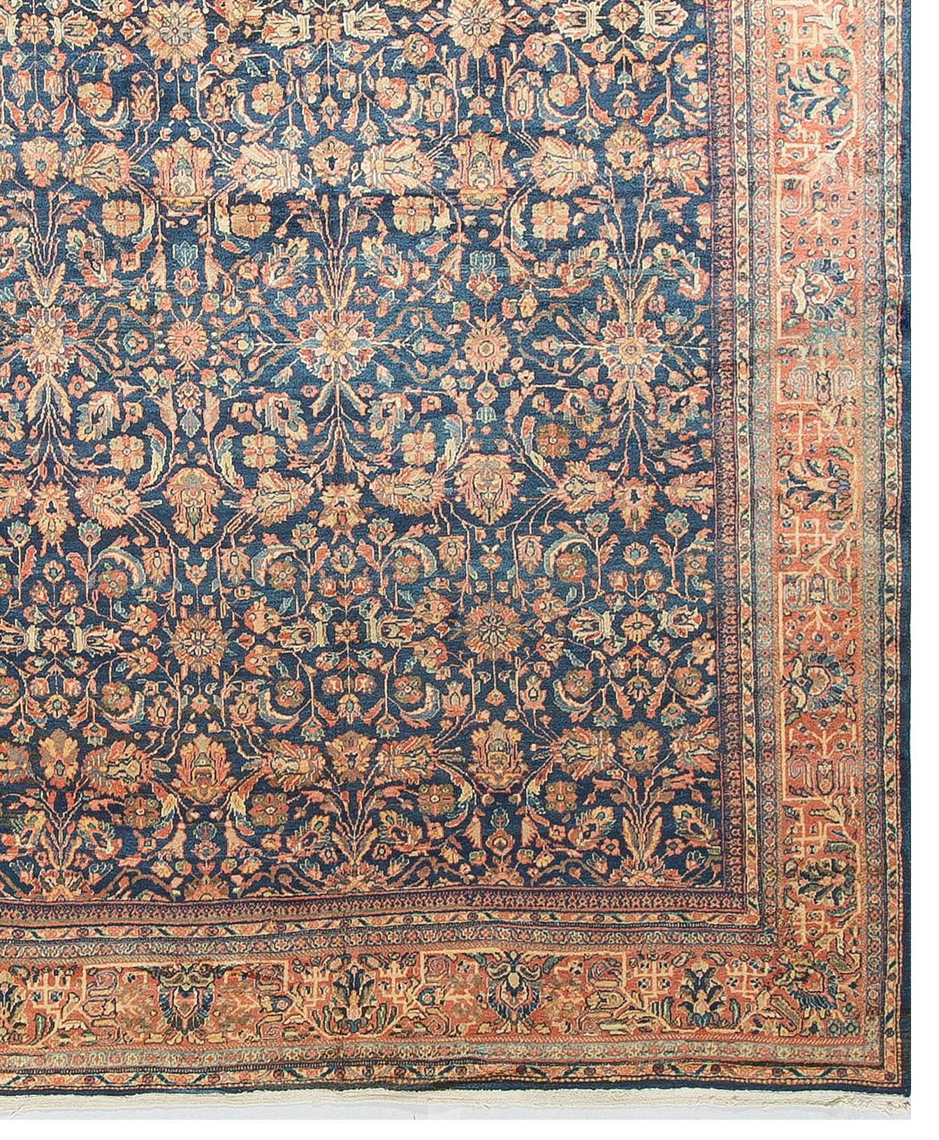 A deep navy field filled with floral designs enclosed by a rust border continuing the floral designs creates this elegant antique hand woven Persian Ziegler rug.