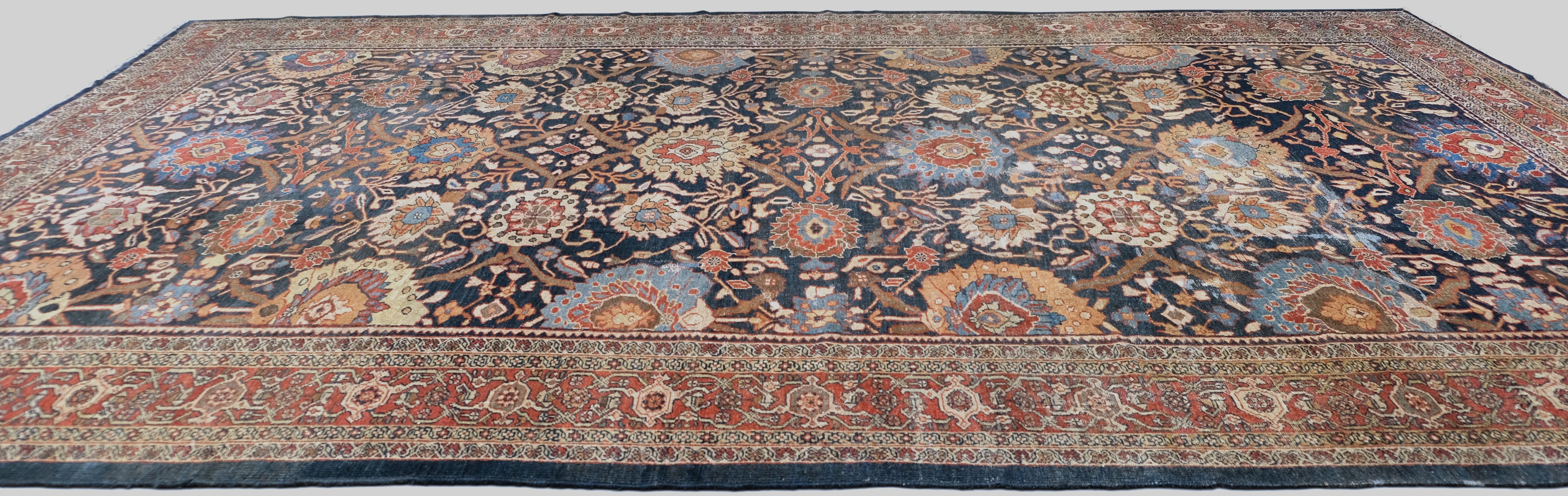 Dieser antike Heriz-Teppich ist ein beeindruckendes Beispiel traditioneller Handwerkskunst. Er wurde im Iran aus hochwertiger Wolle handgeknüpft. Mit seinem satten marineblauen Feld, das mit einem kunstvollen Blumenmedaillonmuster verziert ist,