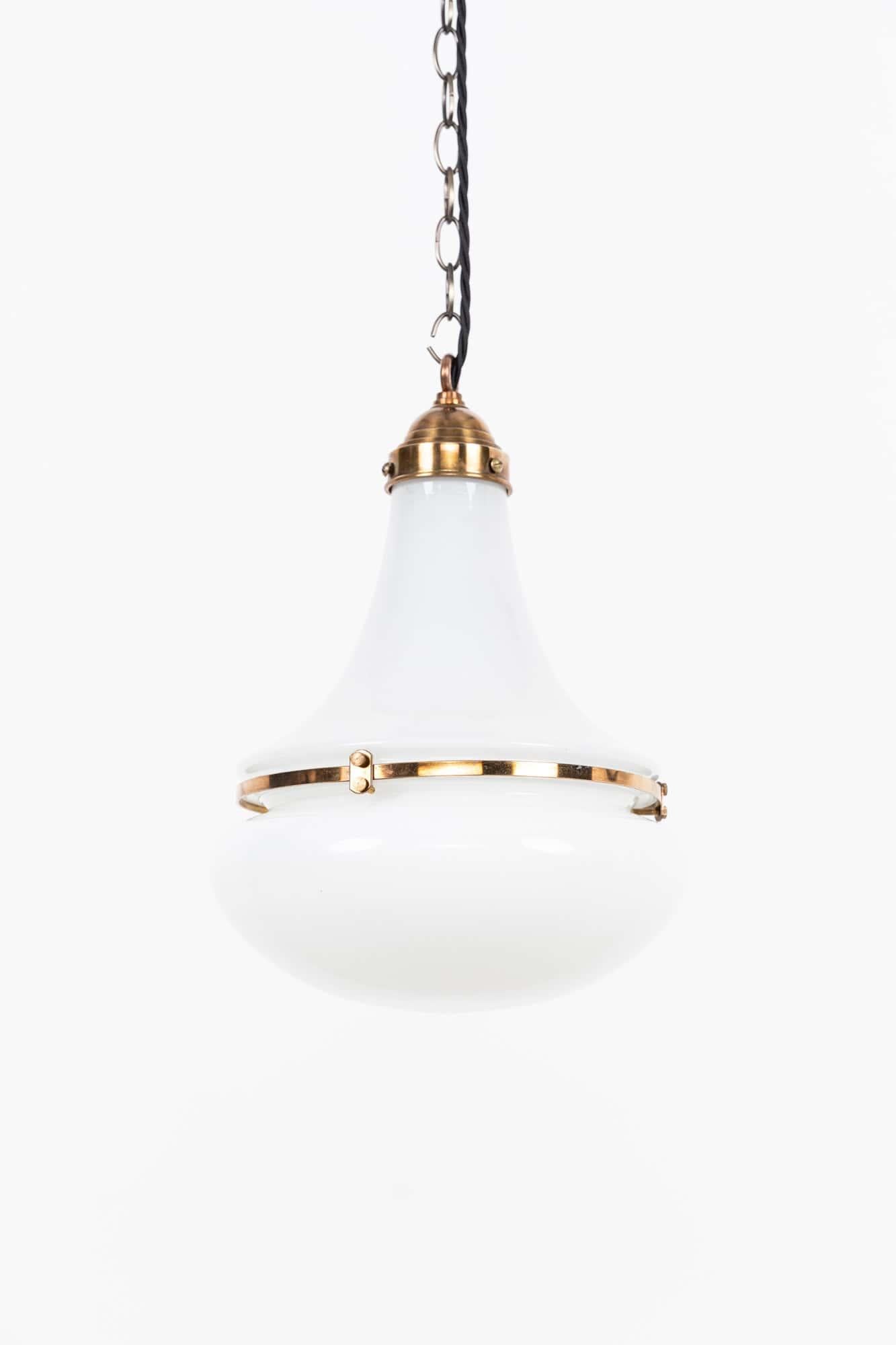 

Un'elegante lampada a sospensione in vetro opalino 'Luzette' disegnata da Peter Behrens per Siemens. Tedesco, 1920 circa.

Paralumi in vetro opalino in due parti sostenuti da un anello in ottone e da una galleria in fusione.  Resti del marchio del