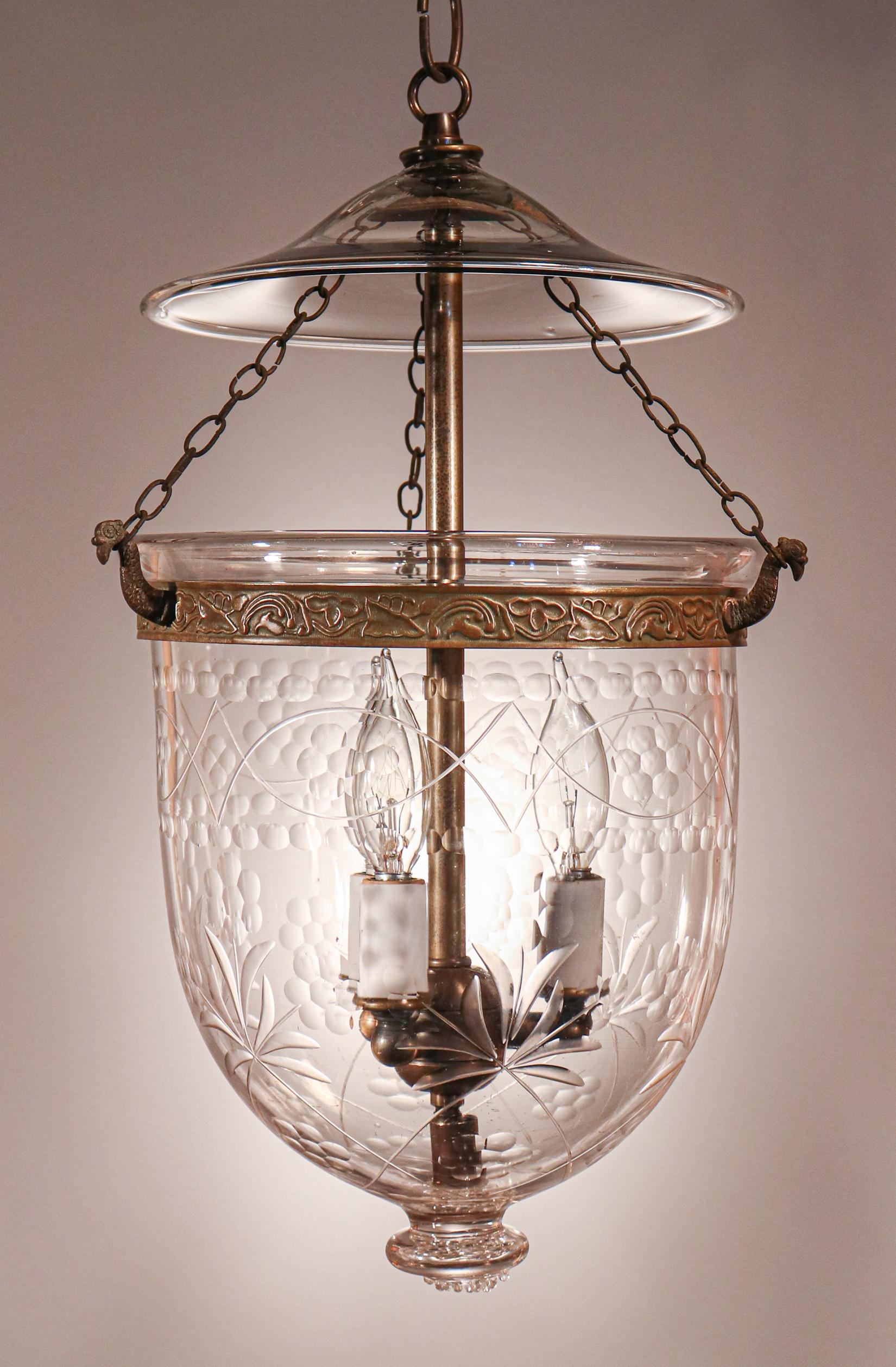 A charming English bell jar lantern with attractive form and an unusual decorative, polished etching. This circa 1890 petite pendant features excellent quality hand blown glass and its original smoke bell/lid and brass chains. The embossed brass