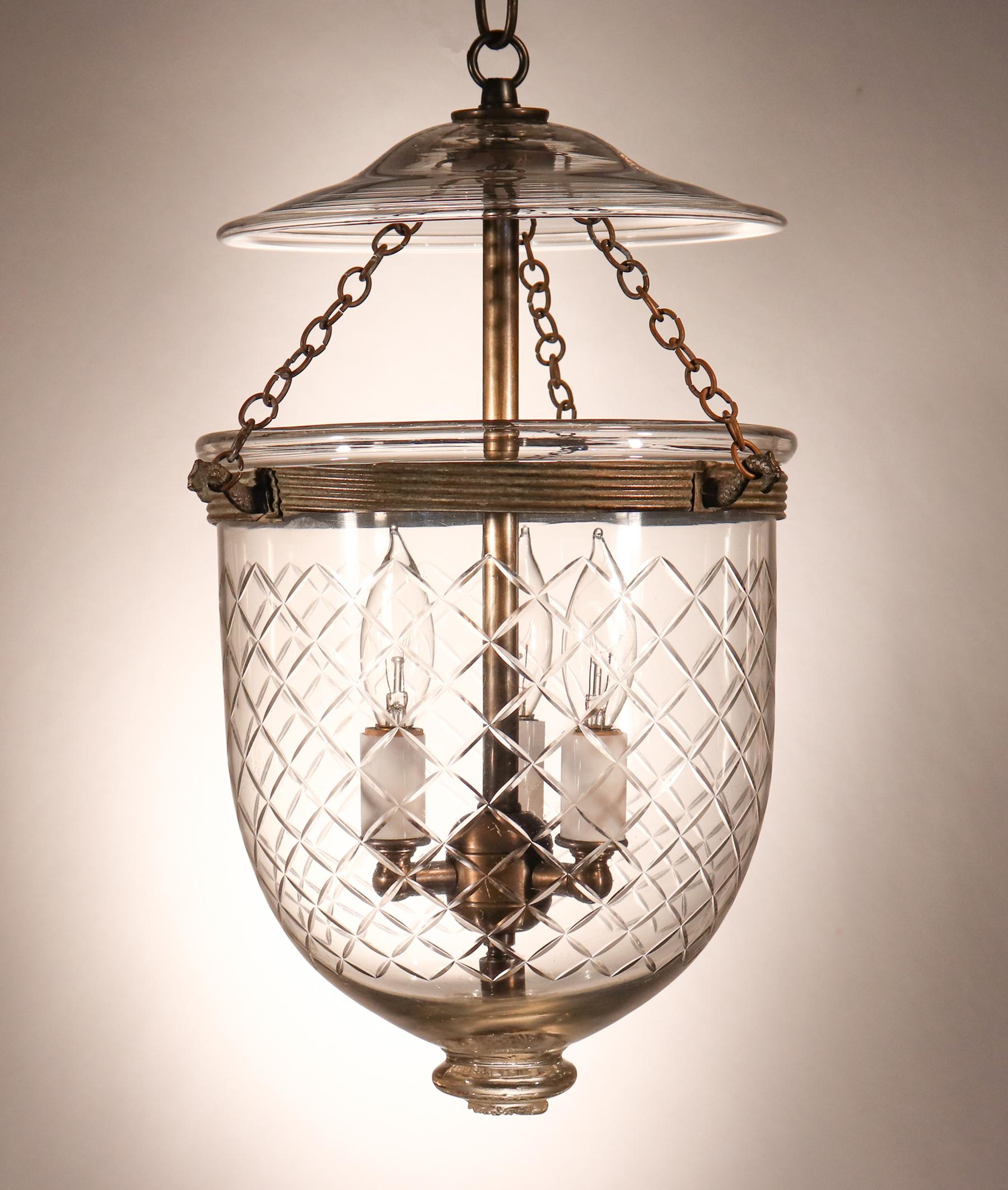 A lovely, diminutive antique English hand blown glass bell jar lantern with a Waterford-style etched, cut glass diamond motif. This circa 1880 lantern features its original rolled brass band and glass smoke bell. The light has been newly electrified