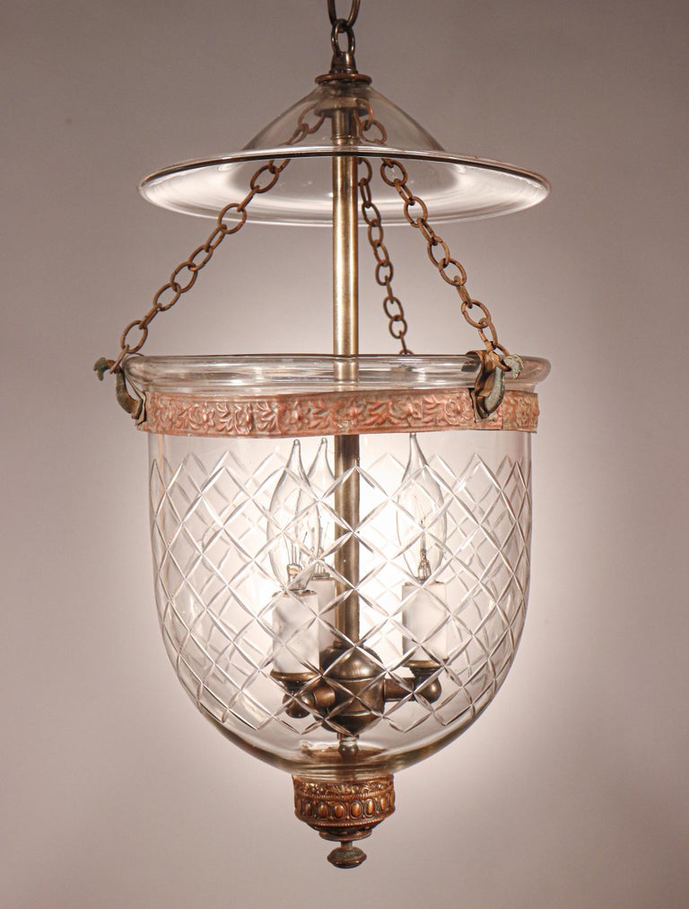 A petite English bell jar lantern with lovely form and excellent quality hand blown glass that is etched with a cut-glass diamond pattern. This circa 1870 pendant features all-original brass fittings—including the embossed brass band and ornamented