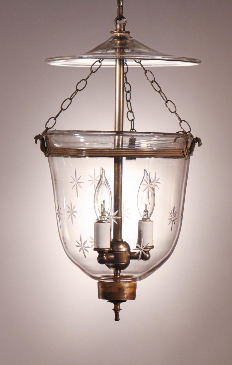 A lovely English petite bell jar lantern with excellent quality hand blown glass etched with a star motif. The lantern features all-original fittings, including its glass smoke bell, brass finial/candle holder base and rolled brass band. The fixture
