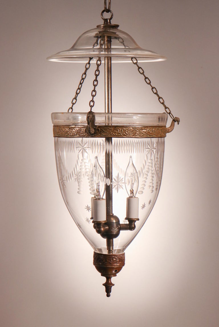 An elegant antique hand blown glass English bell jar lantern with Federal-style etching. This circa 1880 pendant light features an original embossed brass band and complementary replaced brass finial/candle holder base. The fixture has been newly