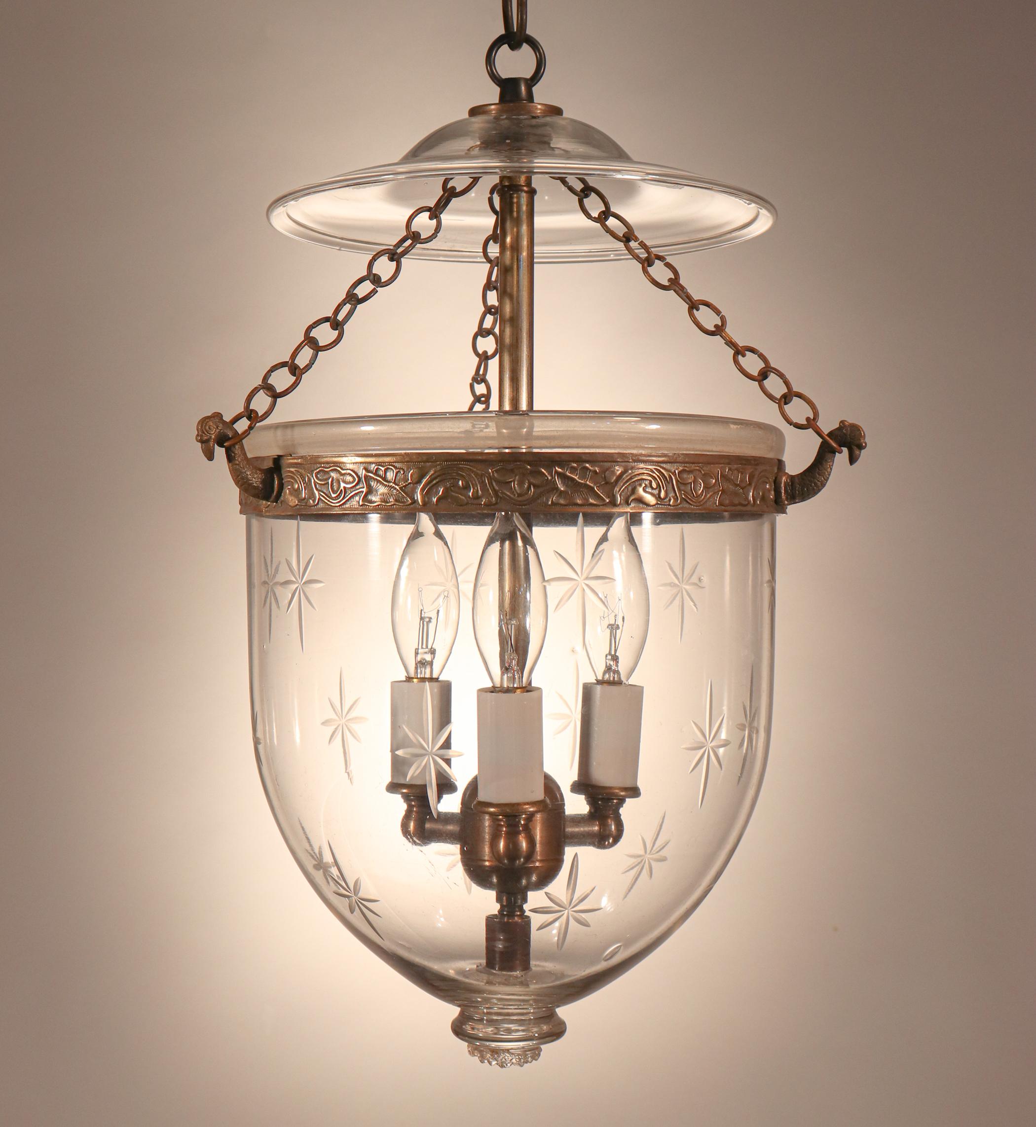 A charming, petite English bell jar lantern with etched stars. Perfect for small spaces and/or low ceiling heights, the pendant features several desirable air bubbles in the hand blown glass, as well as an attractive embossed brass band that was