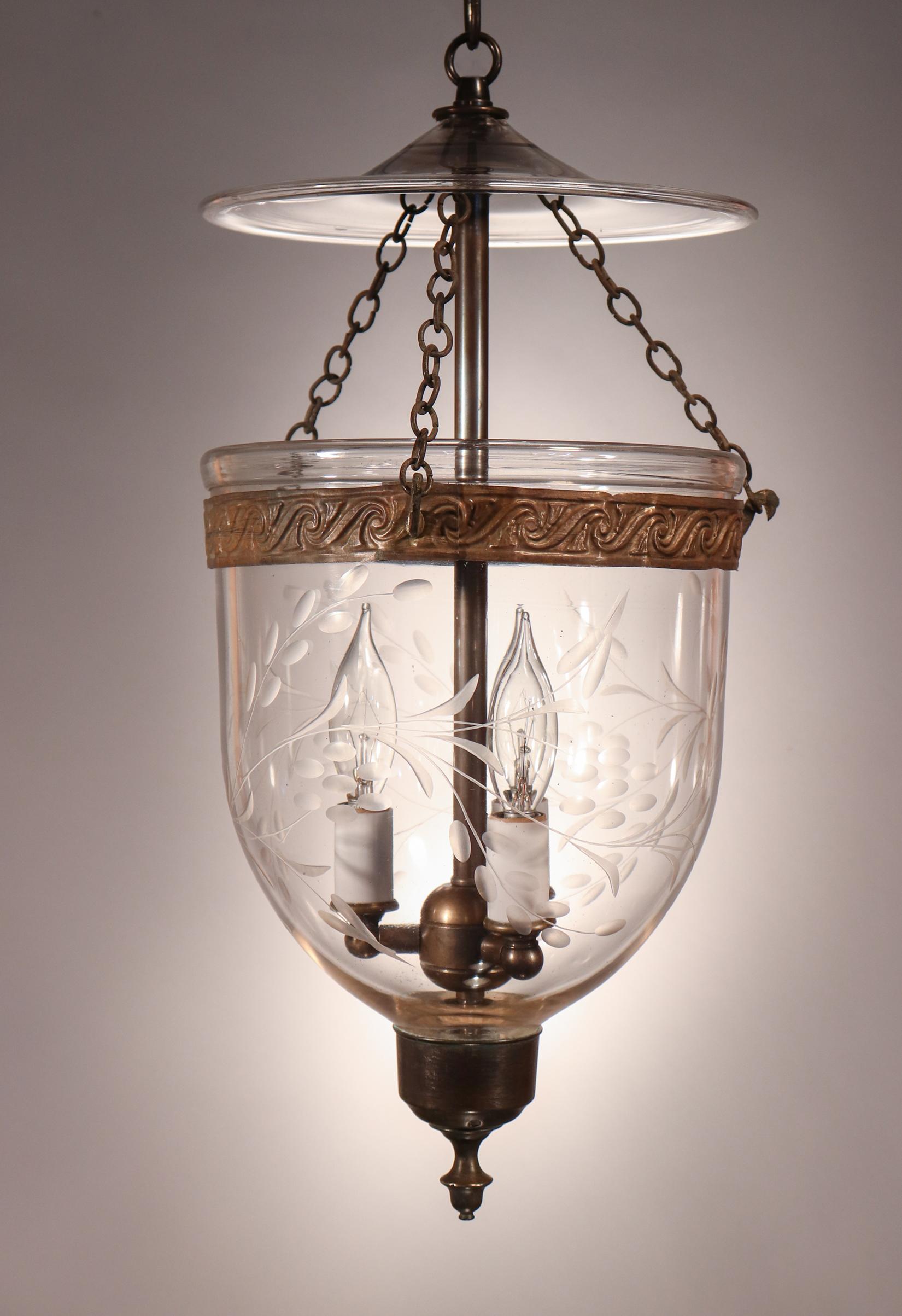 A beautiful antique English bell jar lantern with excellent quality hand blown glass and an etched vine motif. This diminutive pendant features all-original fittings—including its embossed brass band and brass finial/candleholder base. At 8-inches