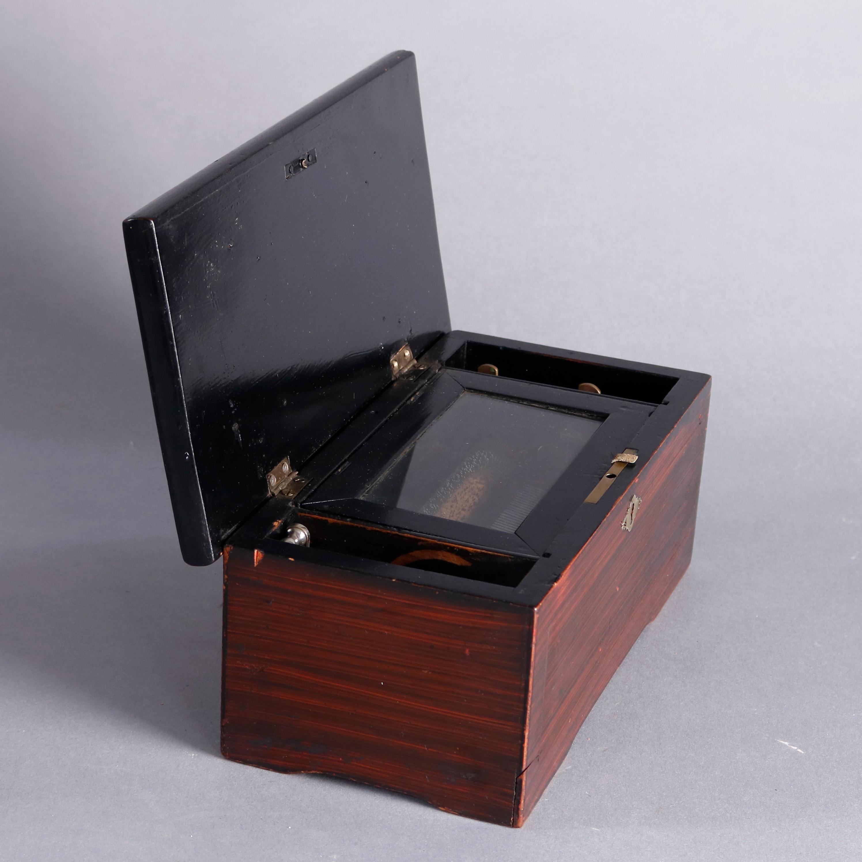 An antique Swiss petite cylinder music box offers grain painted case with top opening to reveal glass covered works, in working order, circa 1890

Measures: 4.75
