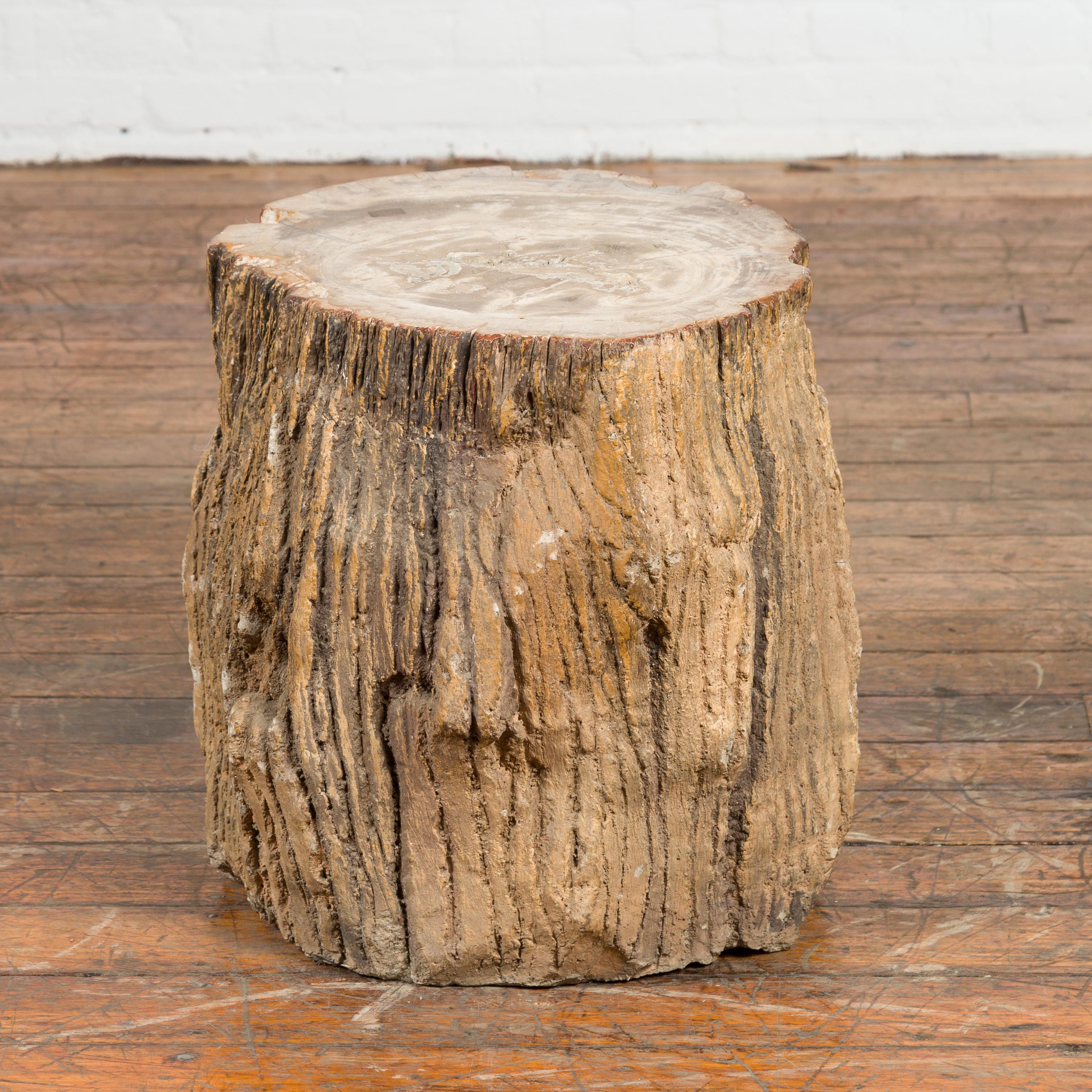 An antique petrified wood tree stump drinks table or stool covered in gesso. Charming us with its grand age and weathered patina, this drinks table will make for a great decorative addition to any home. Petrified wood is the result of a tree having