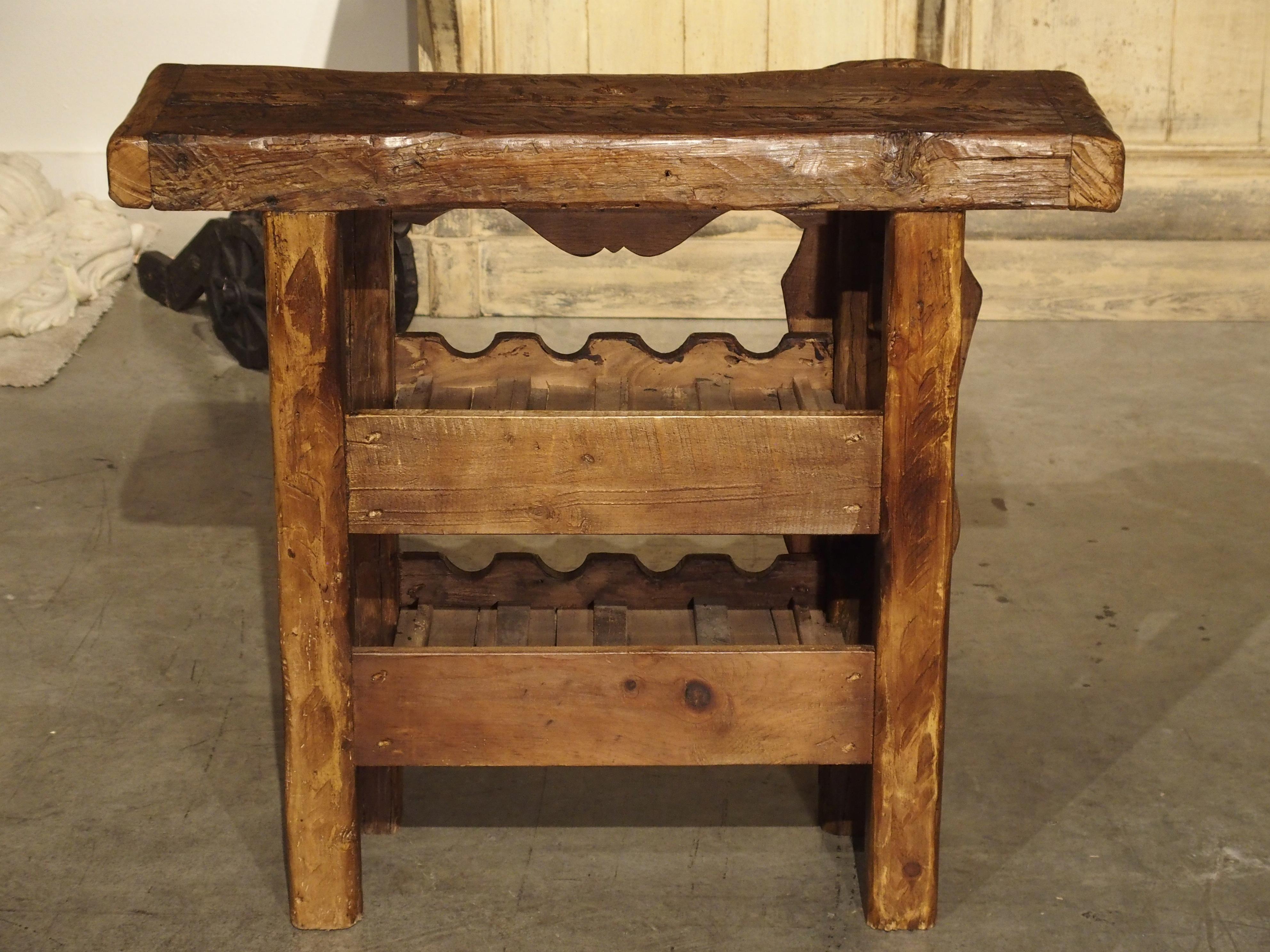 This antique French workbench has been reconfigured into a wine carrier with two rows of bottle holders beneath the thick wood top. There are a total of 8 holders for wine or champagne bottles.

The frontage of the top row reads, Petrus in block