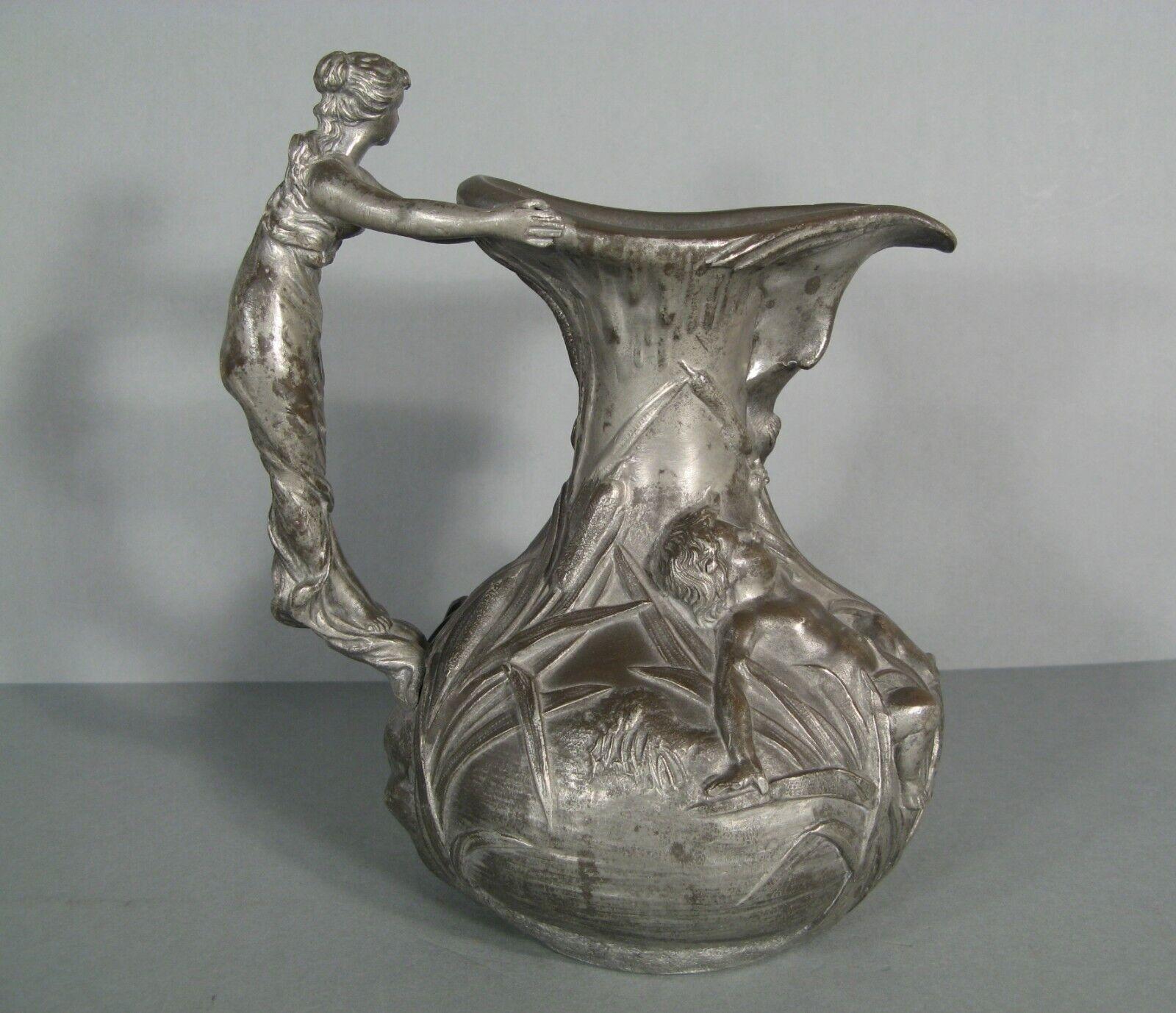 This exquisite Art Nouveau pewter pitcher, designed by Henri Huppé, features a charming motif of putti in a lakeside landscape with reeds and a handle sculpted as a young woman. This piece dates back to the early 20th century and showcases the