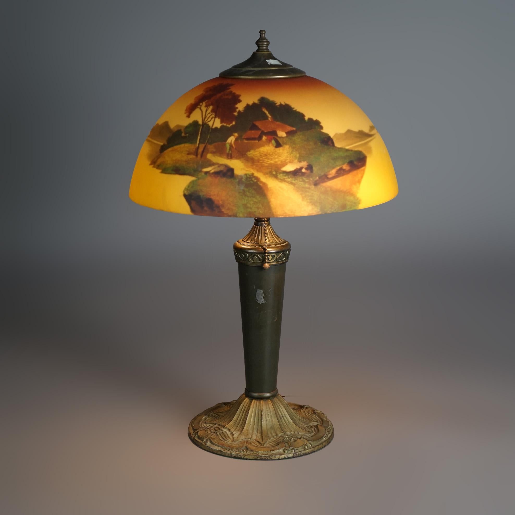 An antique Phoenix table lamp offers reverse painted dome form glass shade having hand painted landscape scene over double socket cast urn form base with bronzed finish, c1920

Measures - 21.5