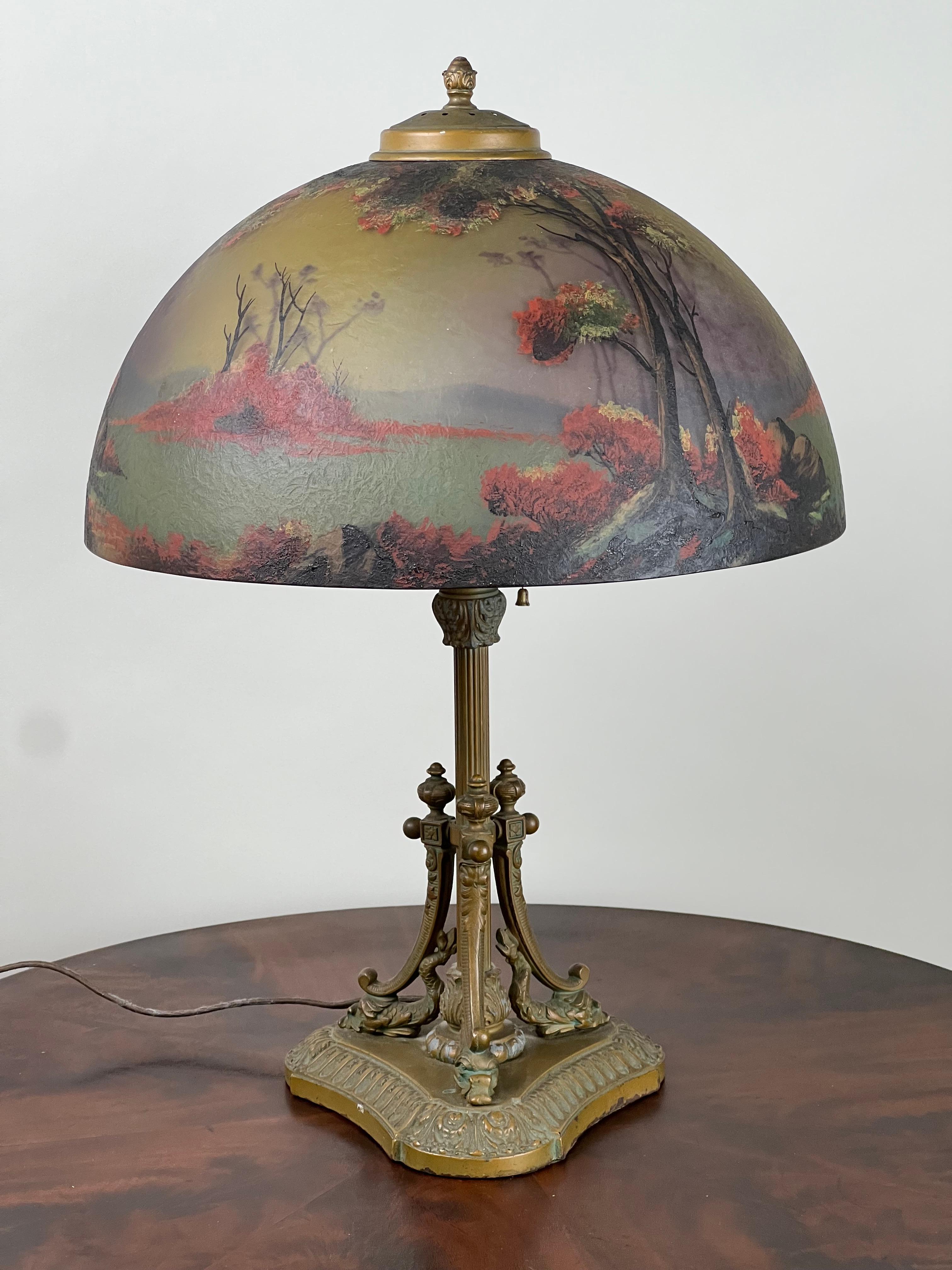 This stunning Antique Phoenix School Arts and Crafts Reverse Painted Lamp by Pittsburgh, c. 1920, features a beautifully painted shade that demonstrates the innovative techniques of the period. The large, dome-shaped shade is painted both on the