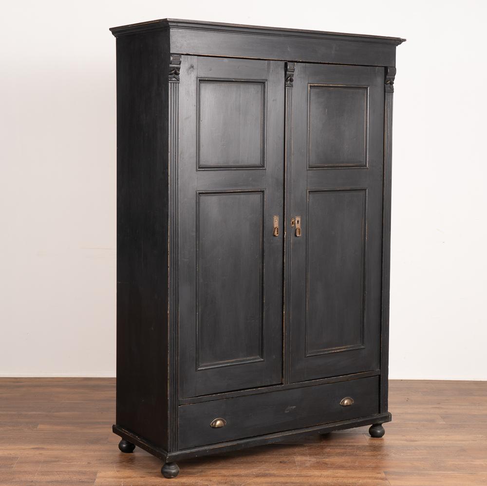 This pine armoire has been given new life with a black painted finish, lightly distressed to fit the age and grace of the cabinet.
One long drawer under the two doors adds additional storage space below the spacious interior cabinet. 
Restored,