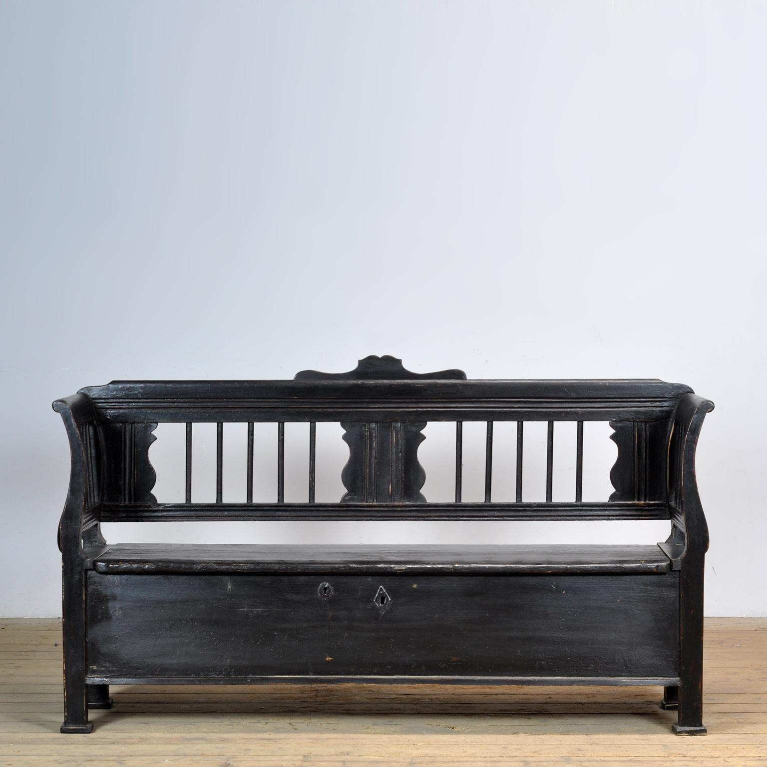 Un charmant banc hongrois datant d'environ 1900. Au fil du temps et de l'utilisation, la peinture noire s'est usée par endroits jusqu'au bois. Avec un espace de rangement sous le siège divisé en quatre compartiments. Le banc est stable et exempt de