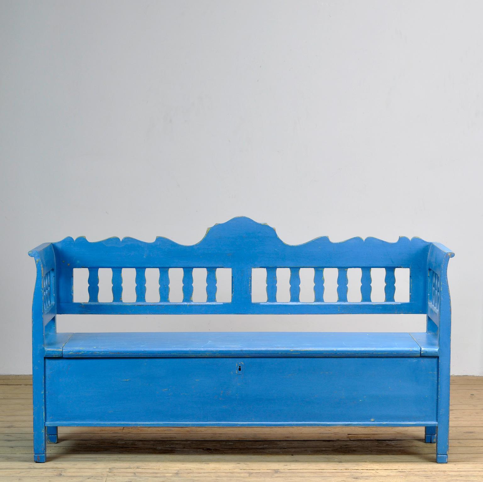 Un charmant banc de Hongrie. Au fil du temps et de l'utilisation, la peinture bleue s'est usée par endroits jusqu'au bois. Avec un espace de rangement sous le siège. Le banc est stable et solide. Exempt de xylophages.
