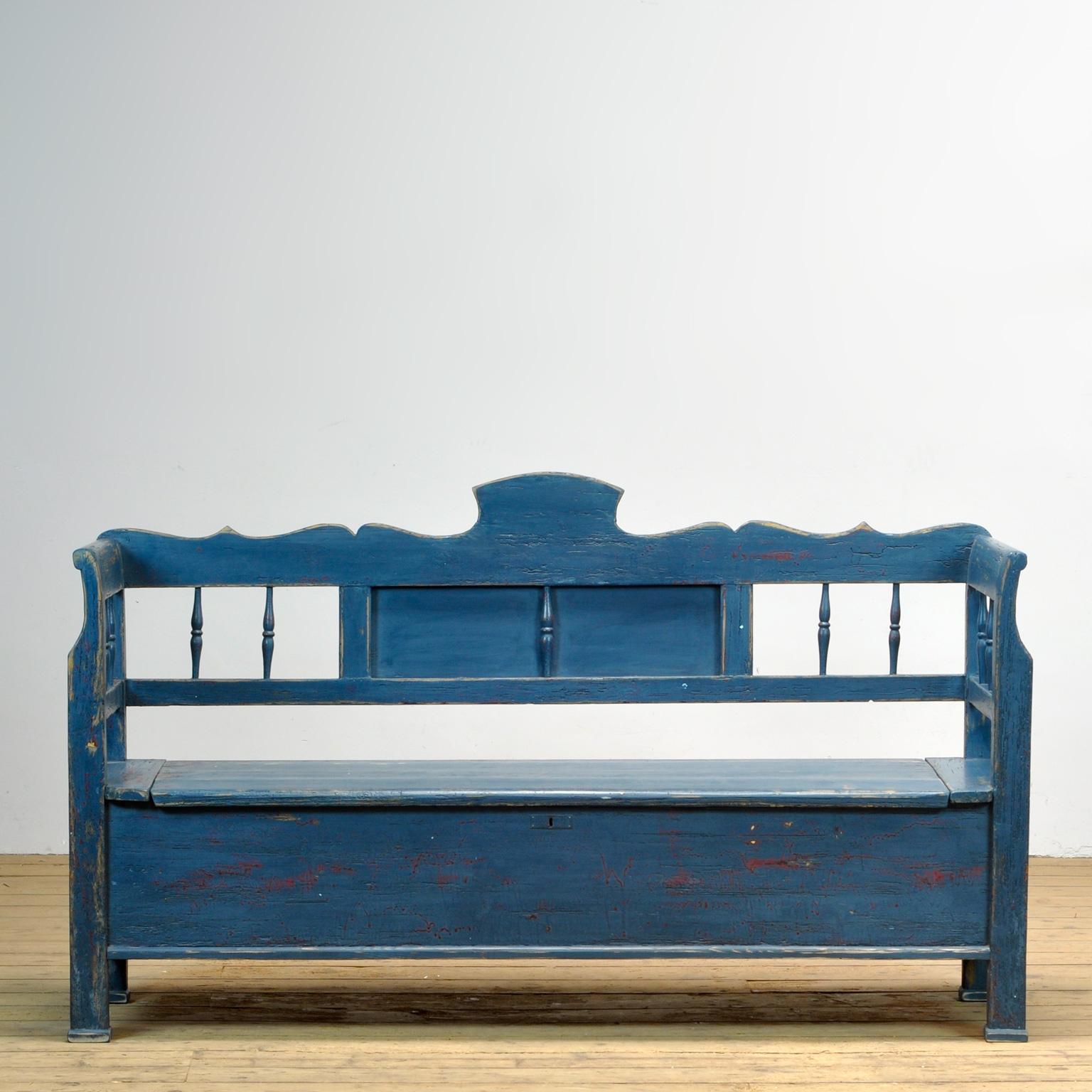 Un charmant banc de Hongrie avec la peinture d'origine. Au fil du temps et de l'utilisation, la peinture bleue s'est usée par endroits jusqu'au bois. L'espace de rangement sous le siège est divisé en trois compartiments. Le banc est stable et