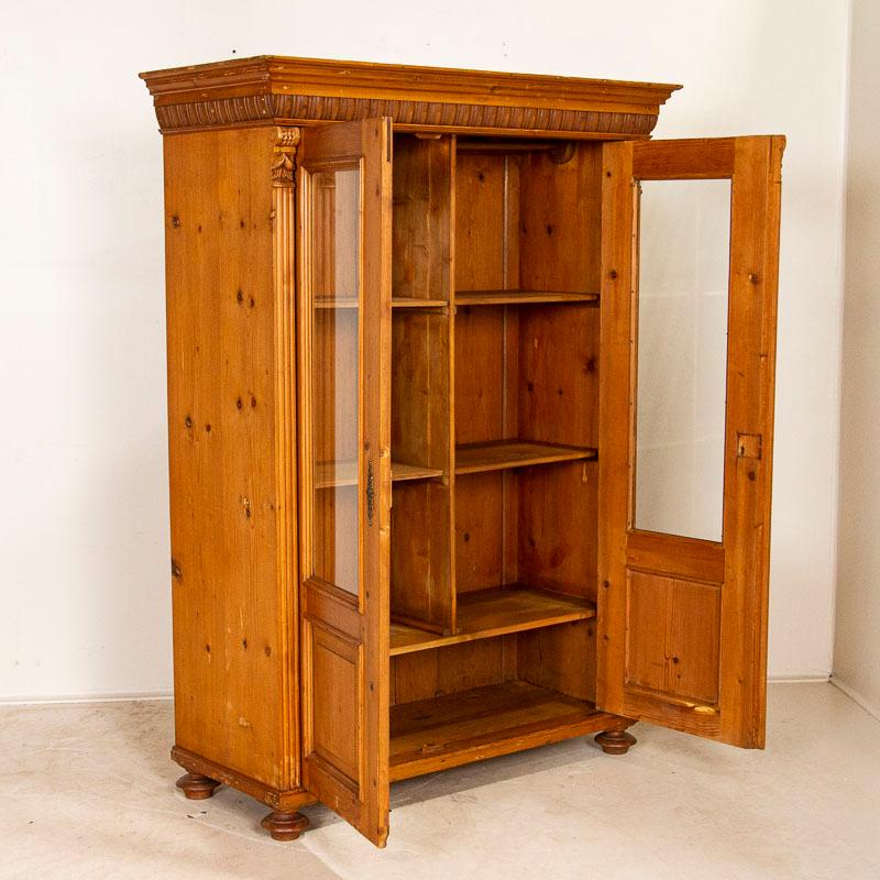 Traditional side trim, bun feet and carving along the crown are traditional style elements seen in this antique pine bookcase. The interior photos show the shelving arrangement; notice at some point a small hanging rod was included in this cabinet.