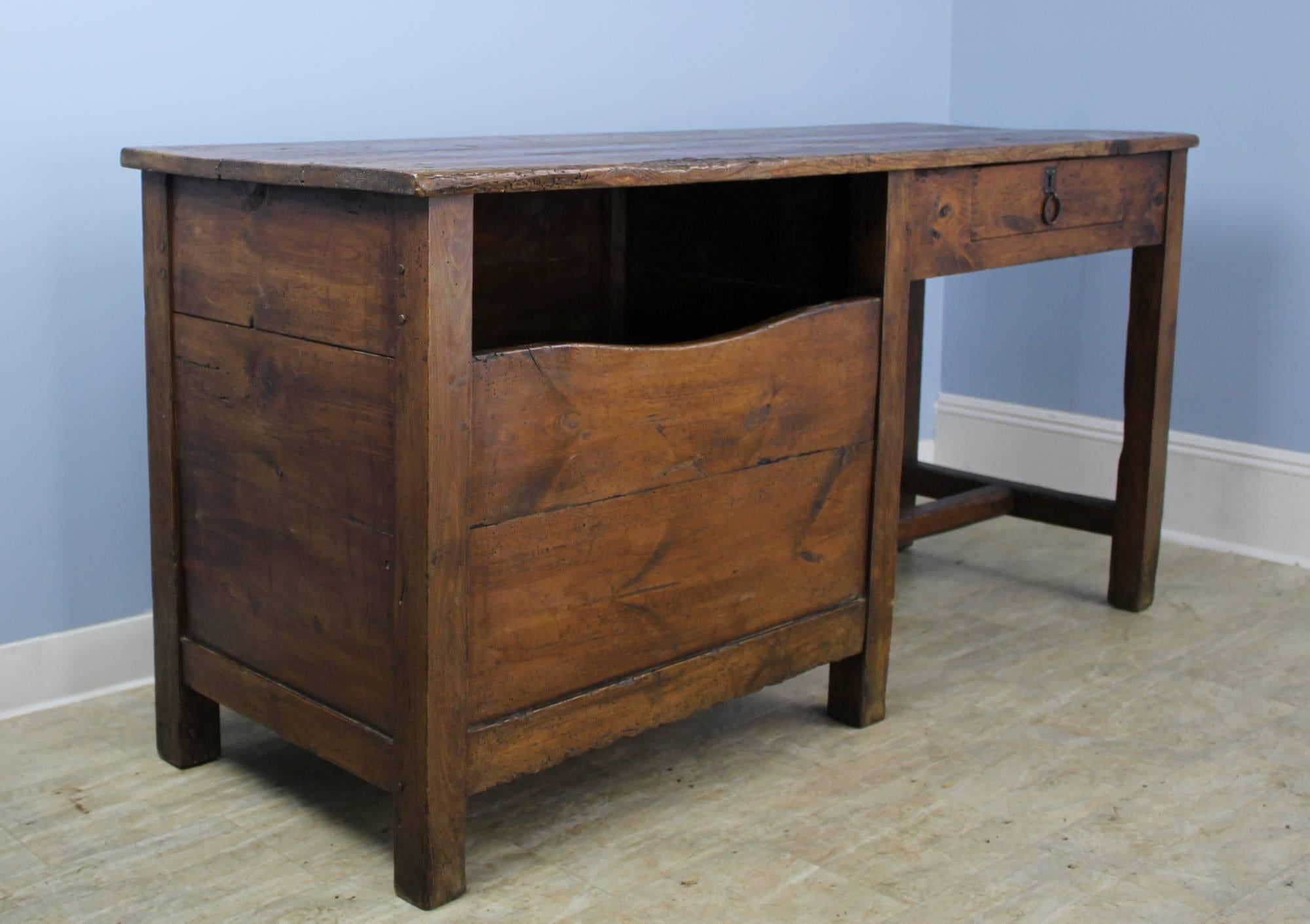 A dark pine breadseller's desk from 19th century, France. This piece is highly functional as a desk, but also has interesting features which reflect it's former life in a bakery, such as a coin slot which leads to the drawer below, and a large
