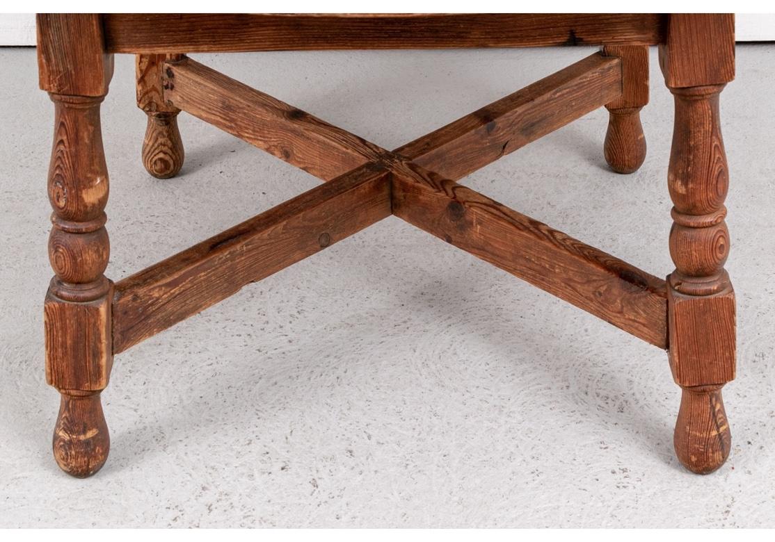 The overhanging top made in four curved sections around the rotating circular center piece. With a broad apron raised on heavy baluster turned legs. The square and turned feet with a heavy X stretcher. Well worn overall from extensive expected use