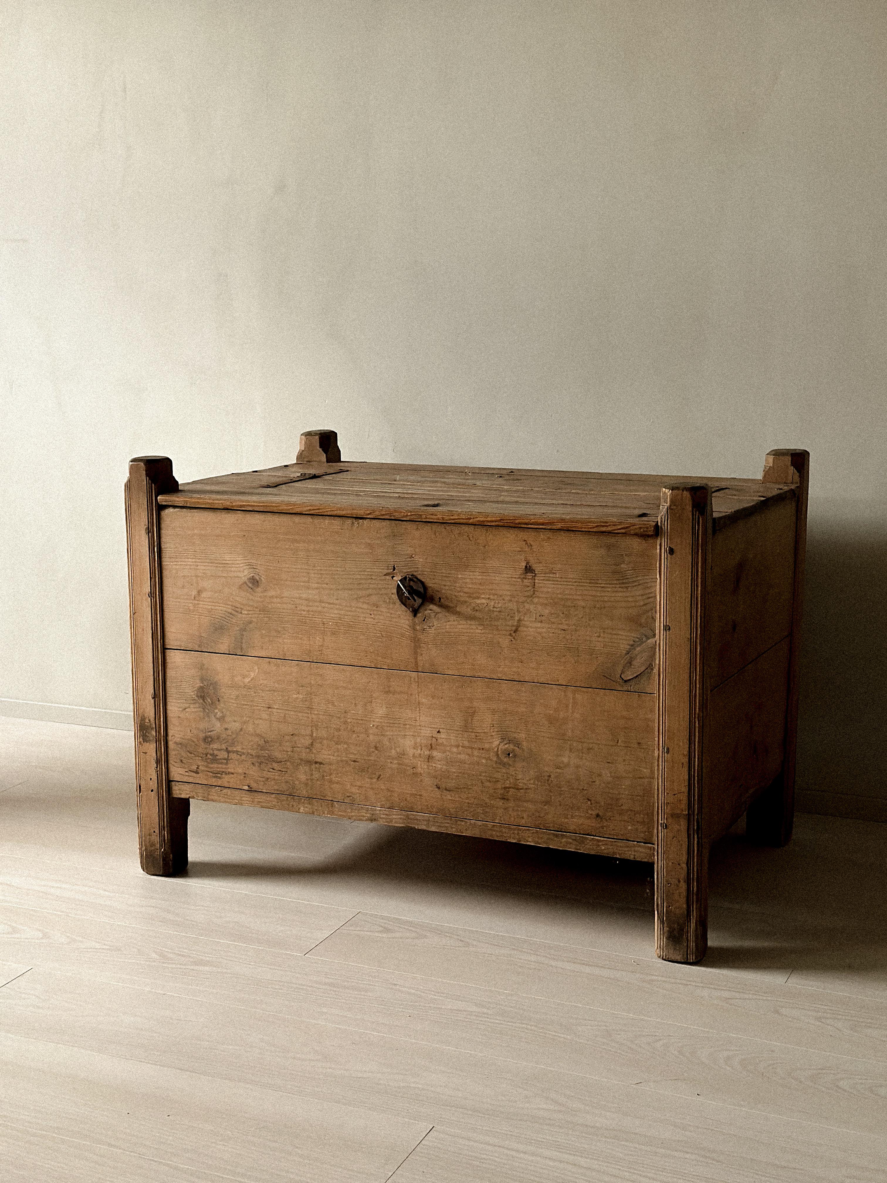 Primitive pine chest, Scandinavia, circa 1700s. Constructed in solid pine with visible joinery and square legs extending above the top board. Warm surface with tool marks, wear, and traces of early repairs. Originally used for storage in a rural