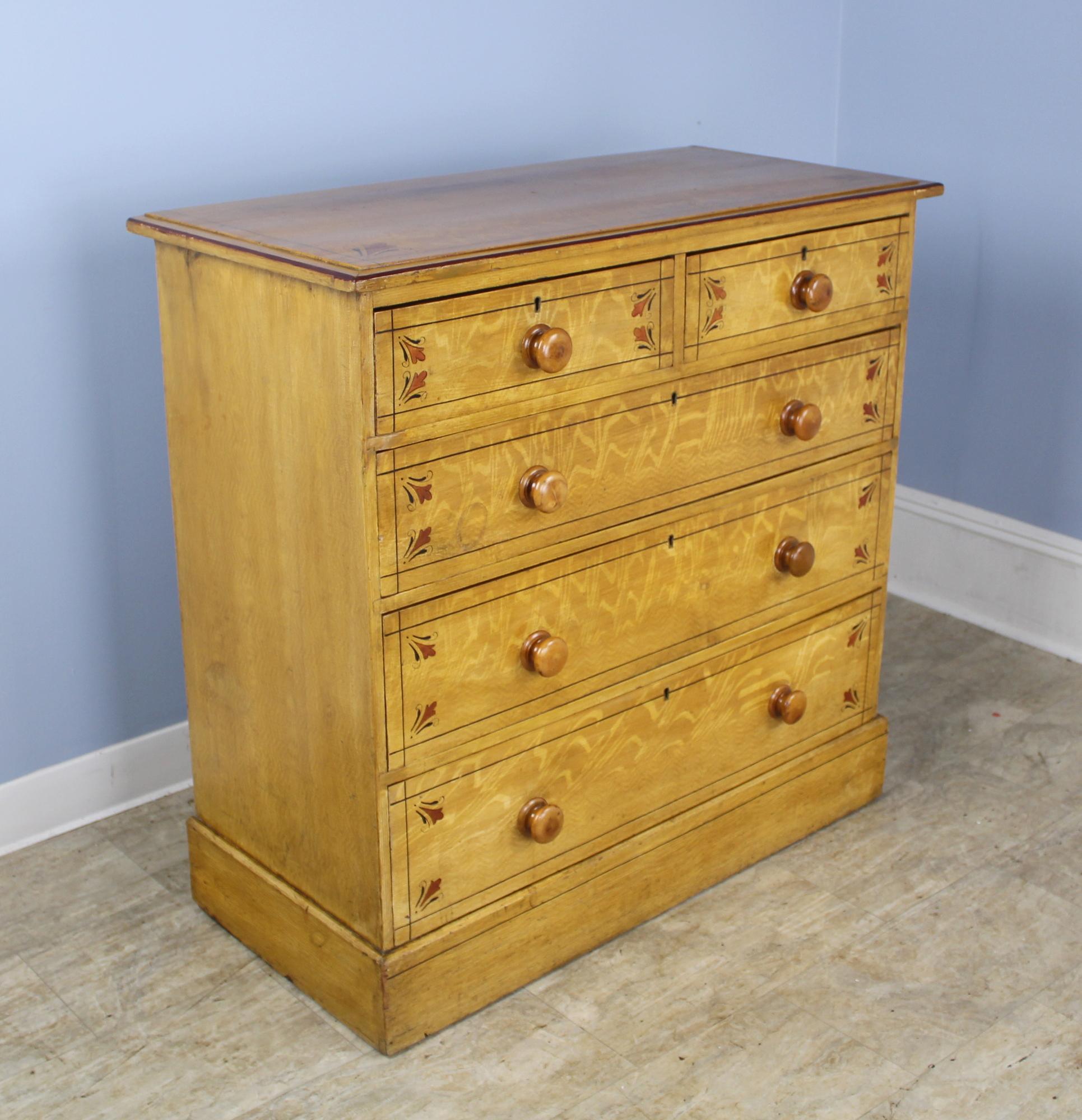 A whimsically hand painted honey colored pine chest of drawers. Charming molded top and plinth. Drawers are clean and slide easily. There is one key that locks all the drawers.