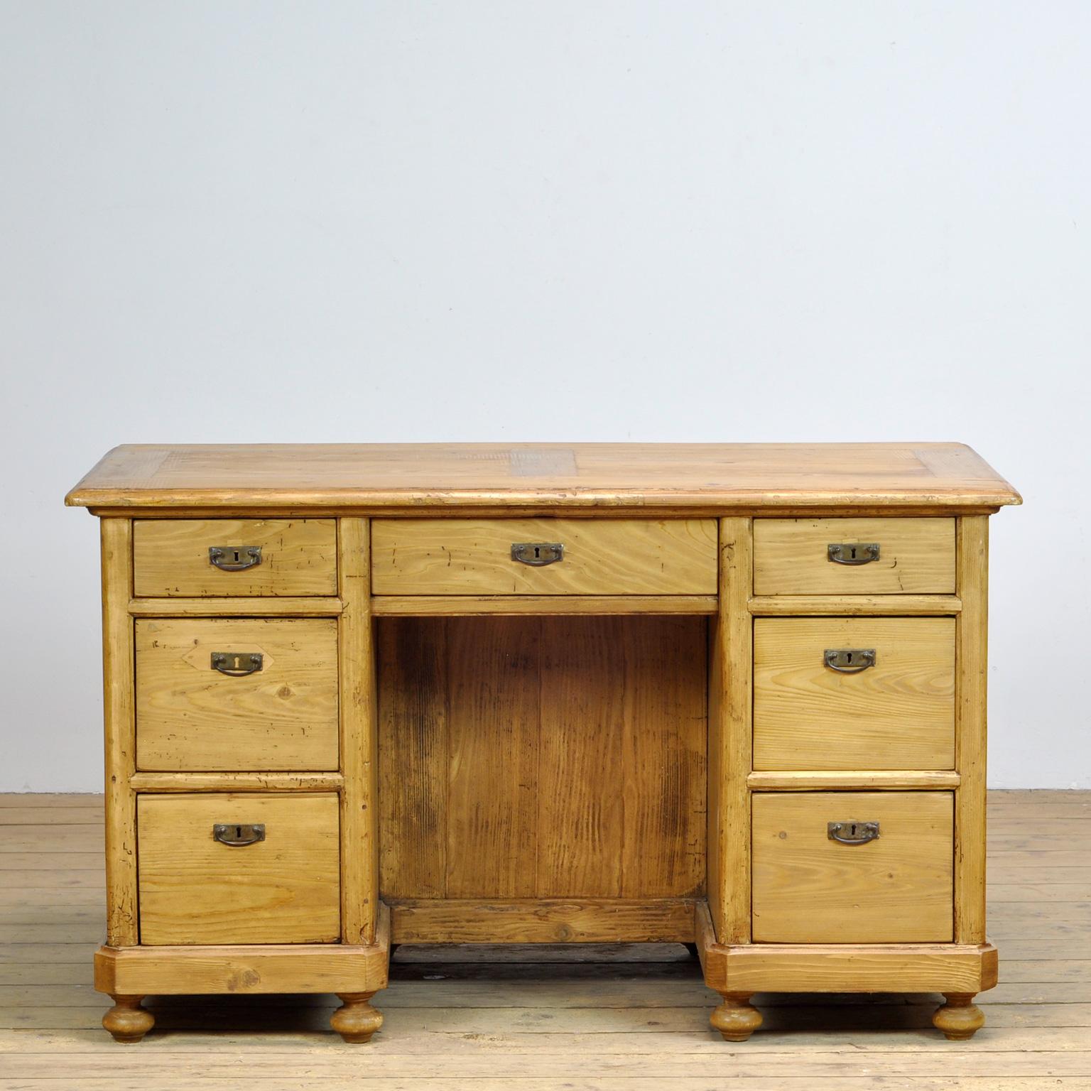 Charming pine desk, European in style. Solid pine, good rustic condition, with cosmetic wear and tear commensurate with age. 7 Drawers in the front, which open and close ok. On the back an other storage space behind a door.