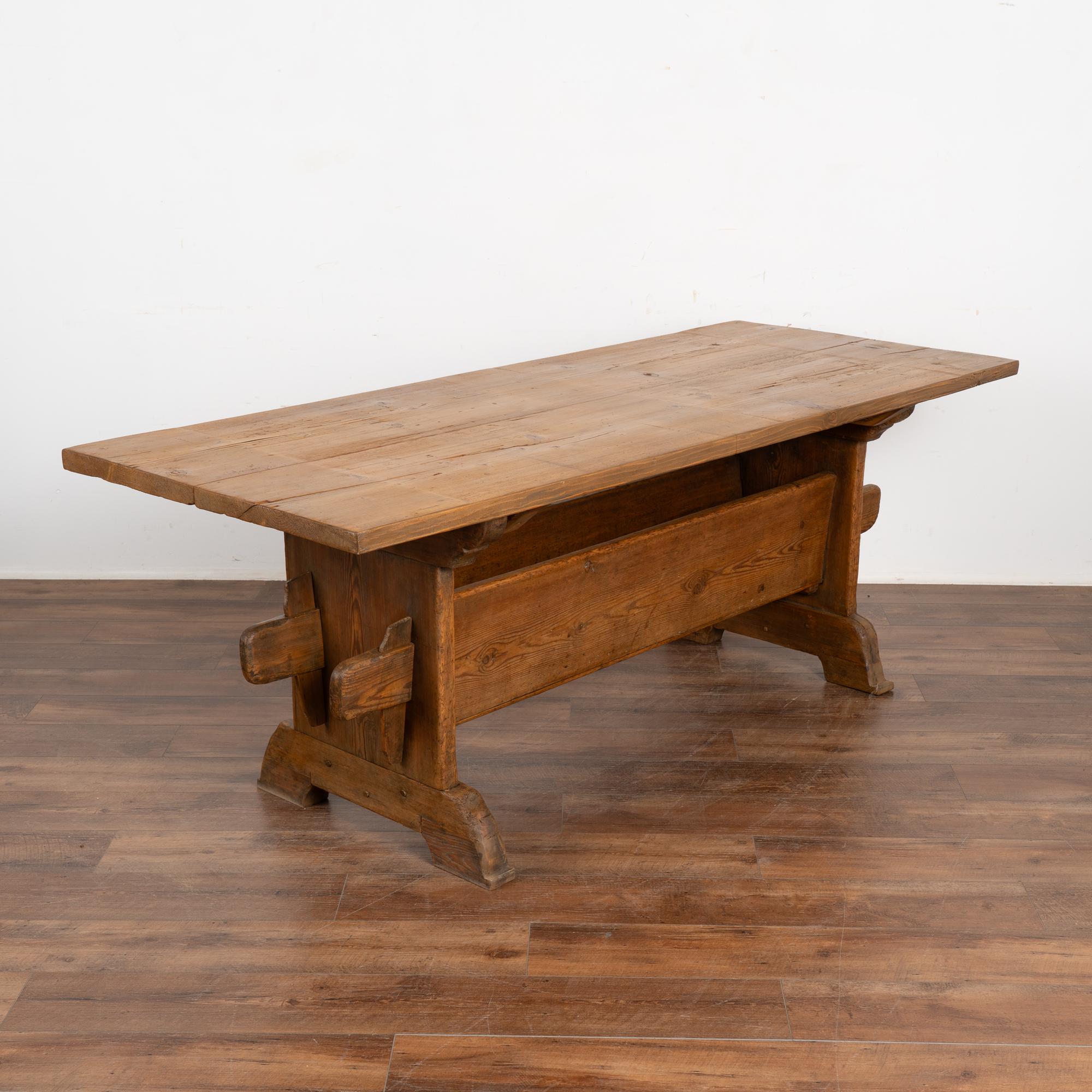 Cette ancienne table de ferme suédoise est pleine de caractère grâce à la patine profonde et vieillie du pin qui provient de générations d'utilisation.  
La particularité de cette table réside dans la largeur de ses brancards, qui mesurent 11