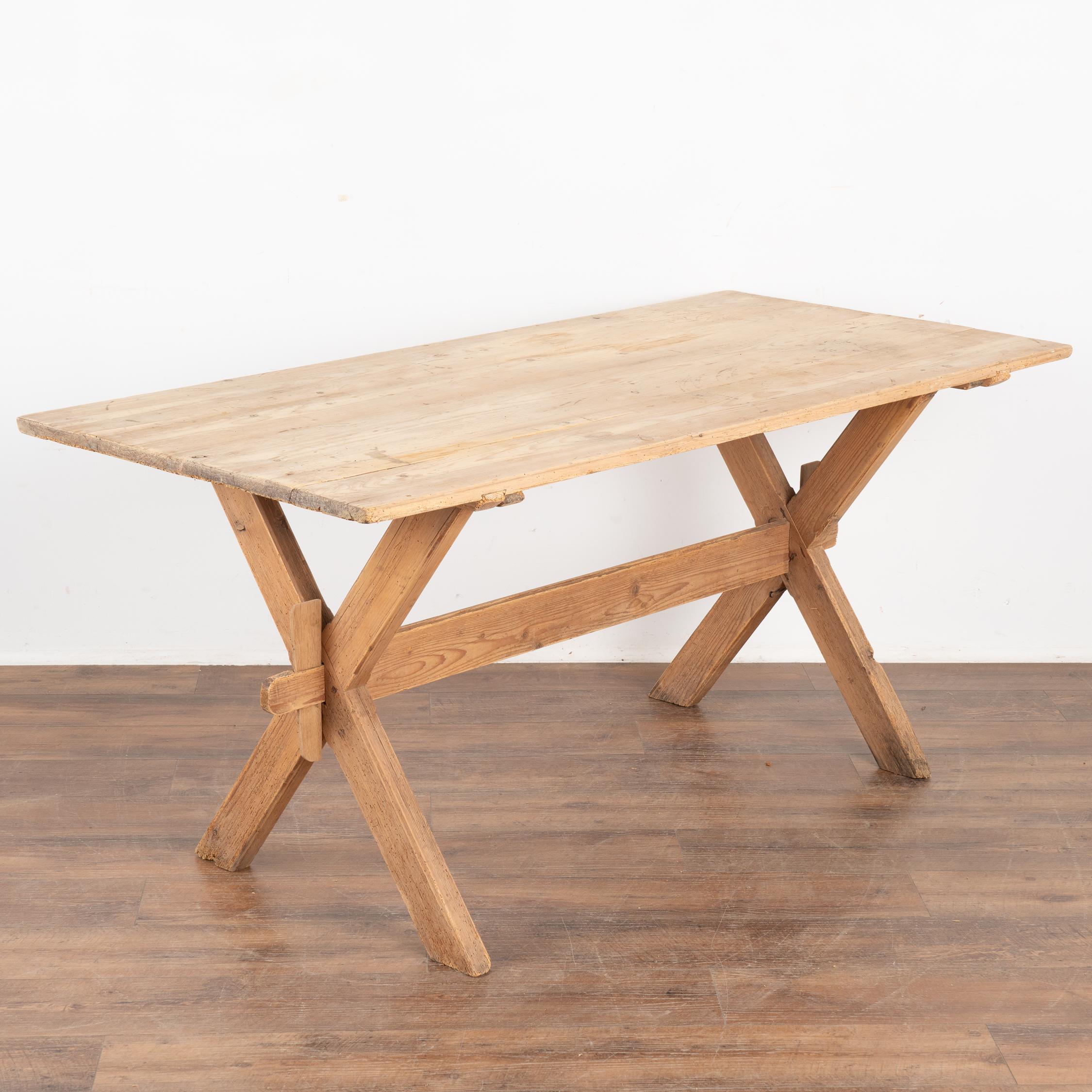This farmhouse dining or kitchen table has European country charm thanks to the unique X-stretcher base.
The natural pine has been distressed through generations of use, adding depth to the character of the table. The many scratches, dings, cracks,