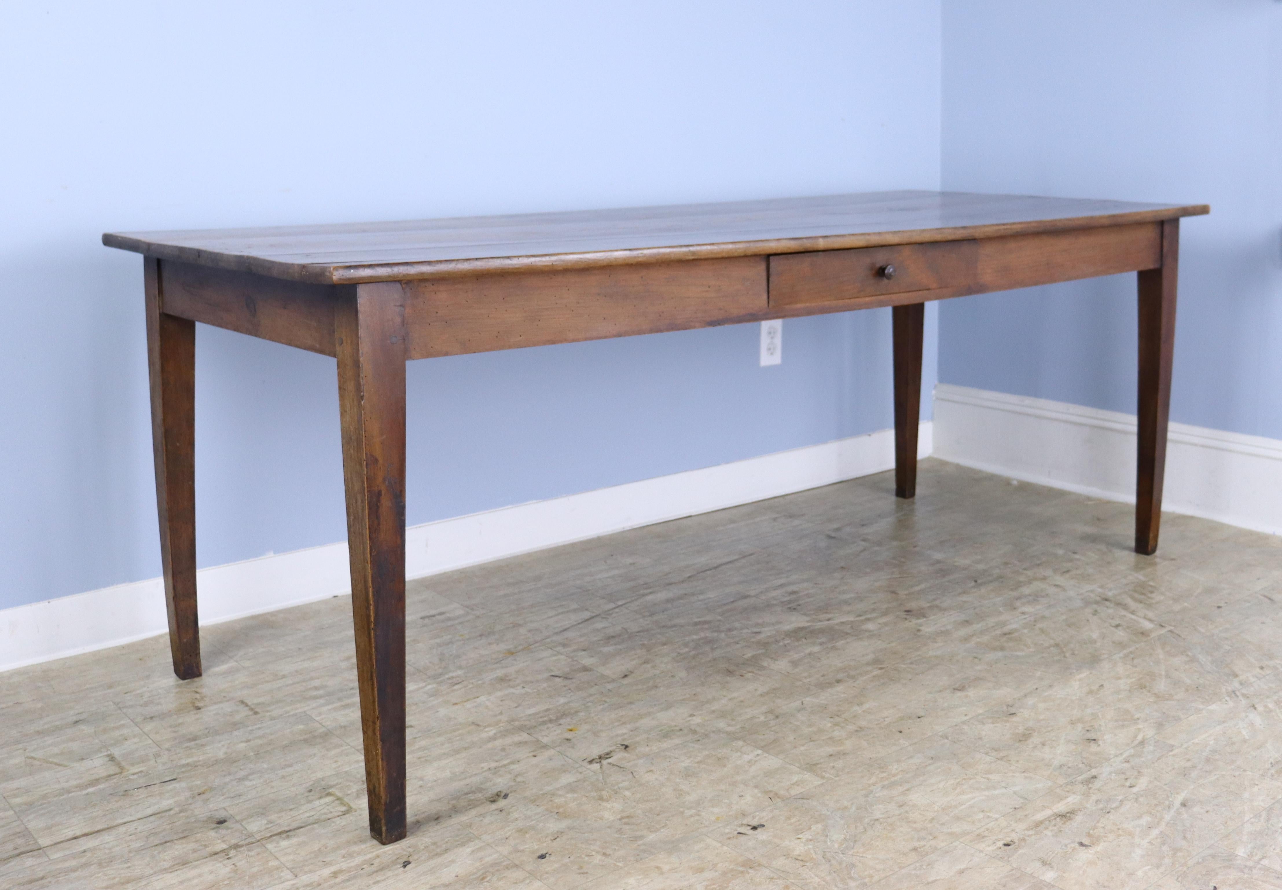A simple elegant pine dining or farm table with good pine grain and color.  The top is is in nice condition and has one old repair, shown in thumbnails.  The apron height of 24 inches is good for knees and there are 70.25 inches between the legs on