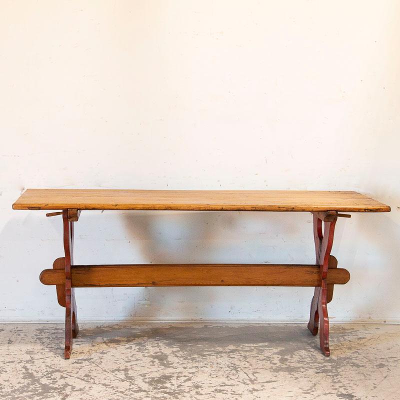 This farmhouse dining table has European country charm thanks to the unique X-stretcher base that still maintains its original red hue that has distressed and faded over generations of use. The natural pine plank top and stretcher (below) provide a
