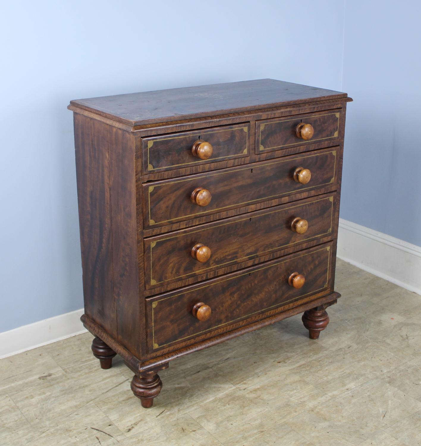 A pine chest of drawers, painted dark with a faux bois look. Whimsical gold painted detail. The chest itself is classic 2 over 3 drawer construction. We love the large knobs and eye catching bun feet.