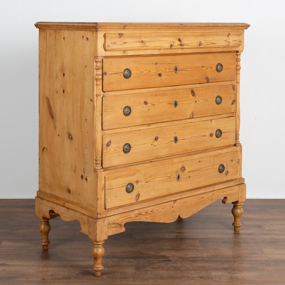Tall empire pine chest of five drawers with half column accents that rests on separate base with four turned feet.
Four larger drawers have two brass pulls; upper narrow drawer has one small pull.
Top drawer is secured by hidden wood 