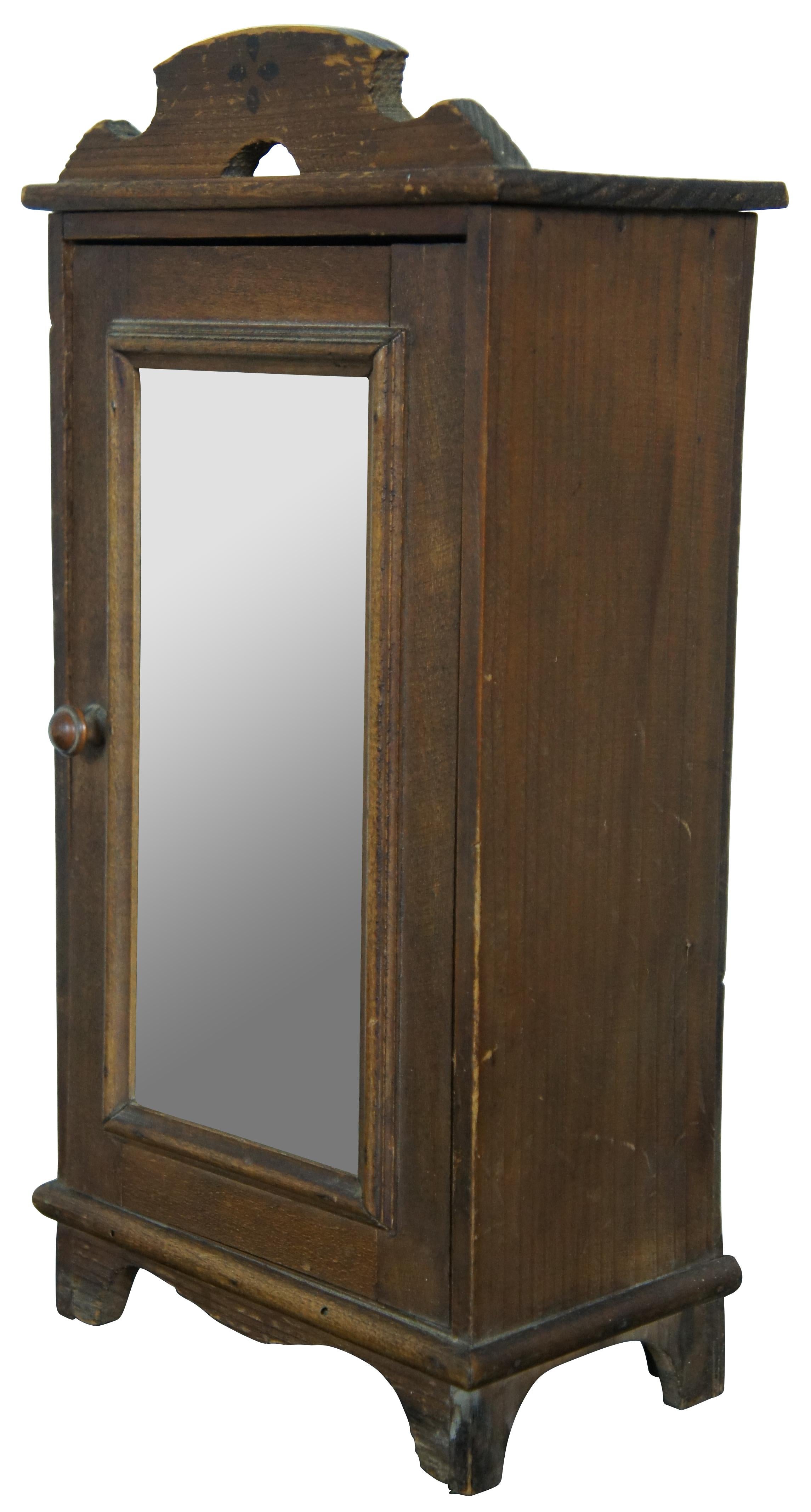 Penderie ou armoire ancienne en pin du 19e siècle, avec porte en miroir, une étagère à l'intérieur et un fronton sculpté à la main avec une fleur d'art populaire à quatre pétales. Mesure : 14