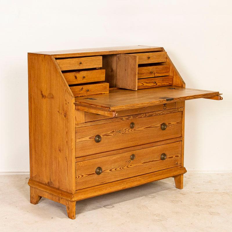 This pine drop front secretary is charming in every way, with a soft, satin wax finish that compliments the aged pine and Swedish country styling. The interior 6 drawers and one cubby w/door are all flush with each other making for a larger writing