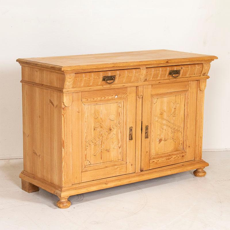 This pine sideboard was a traditional element in farmhouses throughout the 1800's in Europe. The decorative floral carving in the panel doors add a touch of European country charm. It has been restored so it is strong/stable and given a wax finish
