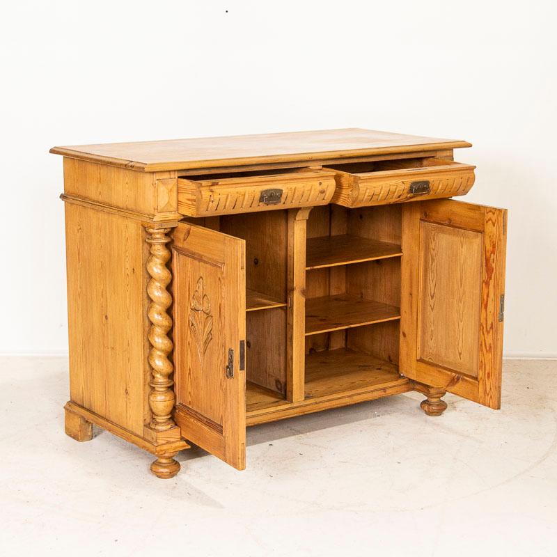 The warm pine glows in this lovely sideboard from Denmark. The dramatic turned barley twist columns and carved flowers in the panel doors add to its appeal. This sideboard has been restored; the drawers run smoothly and entire piece has been given a
