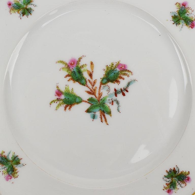 A fantastic antique floral ceramic dish, begging to be displayed at a chic dinner party. A floral bouquet of pink and green takes center stage at the middle on a crisp white background. Along the outer rim, four complimentary floral decorations