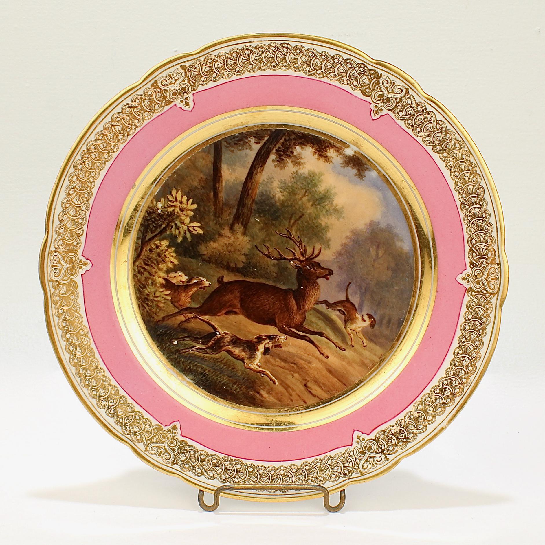 A wonderful antique 19th century Paris porcelain plate.

With a hand painted scene of a hunt scene in a bucolic landscape including a large buck (10 point) and 3 hounds in chase. 

It has a rich pink border and an elaborate gilt design to the