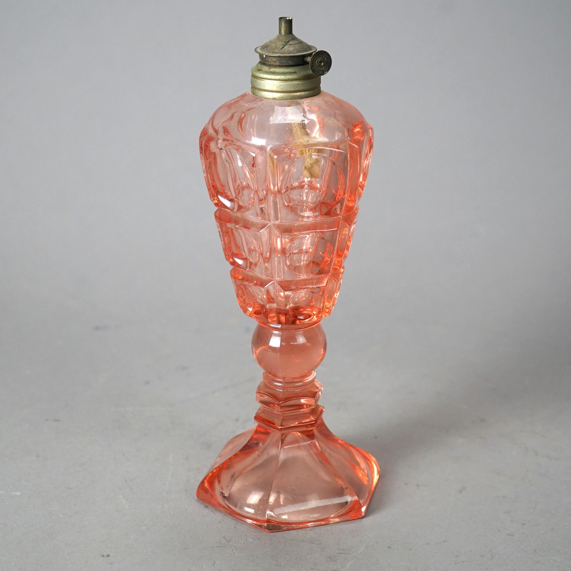 An antique oil lamp offers pink pressed glass construction with paneled coinspot pattern raised on column with hexagonal foot, c1840

Measures - 10
