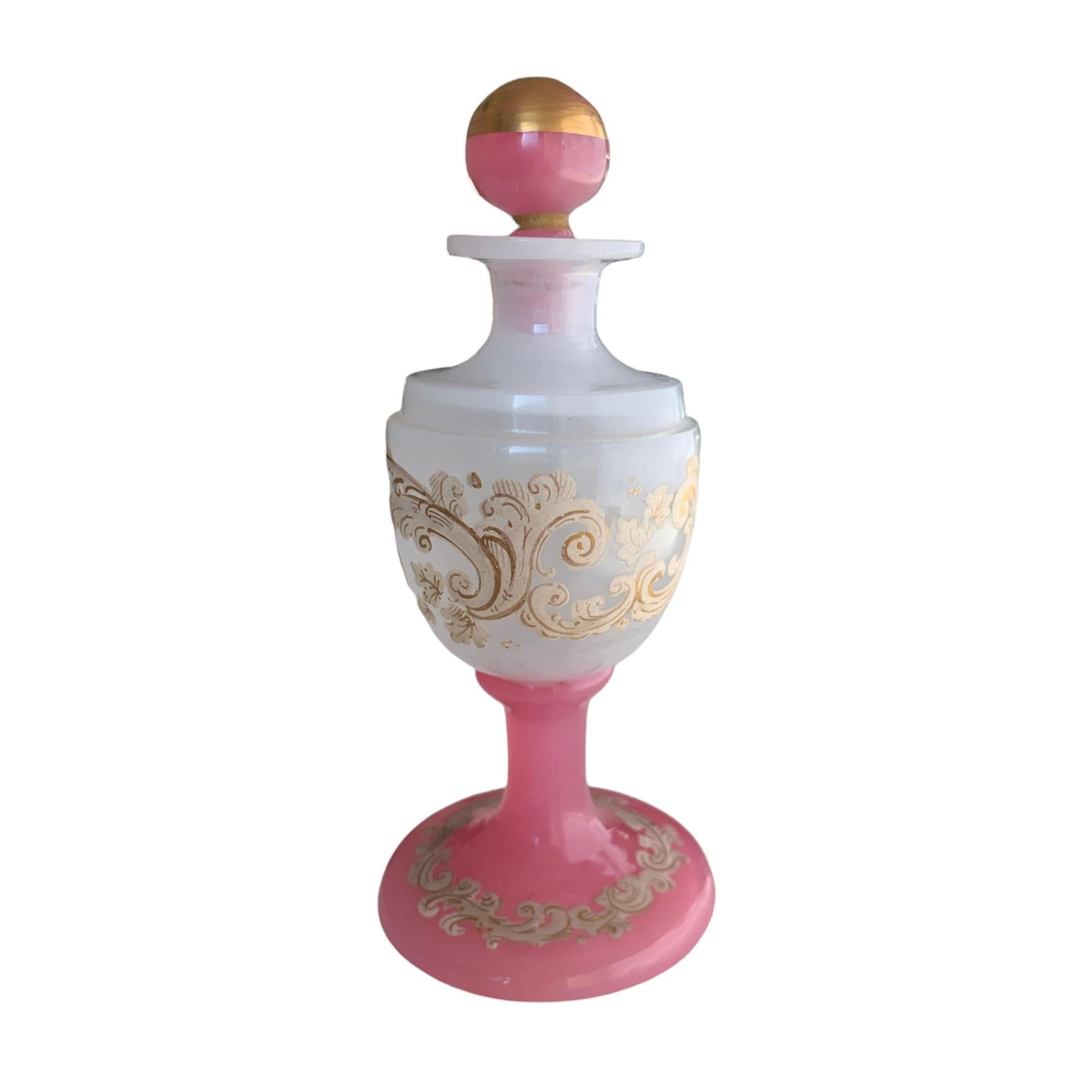 High quality perfume bottle and stopper made of two-colored opal glass with gilded enamel decoration, the milky white circular body features continuous scrollwork enameling, set on a spreading pink foot with further enamel-decoration forming a