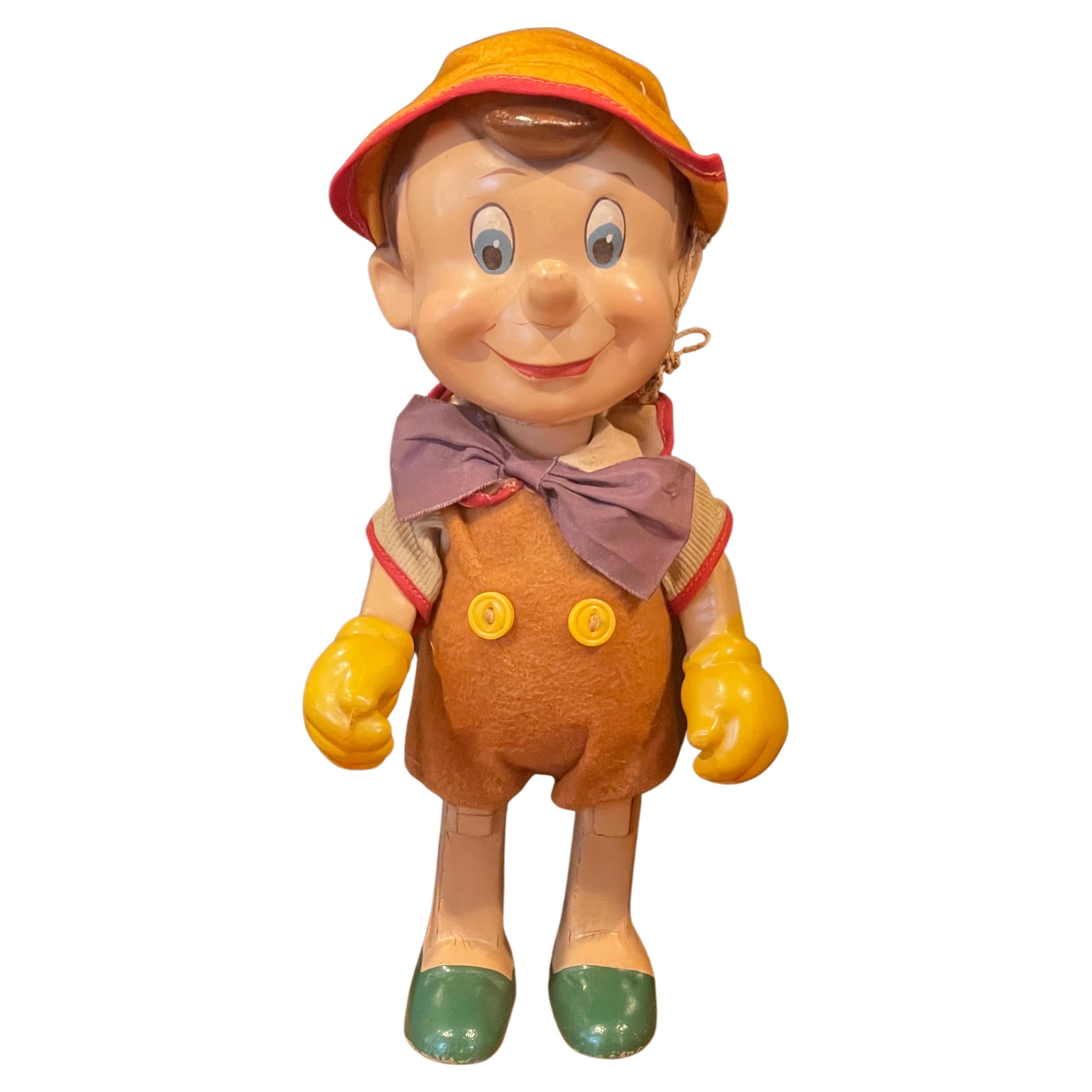 A vintage composition Pinocchio doll by Knickerbocker Toy company, likely from the 1930s. The doll’s back is embossed with “Pinocchio - W.D. PR KNT CO - Copyright U.S.A.” The composition doll has moveable arms and a moveable head. Measuring 4.75” W