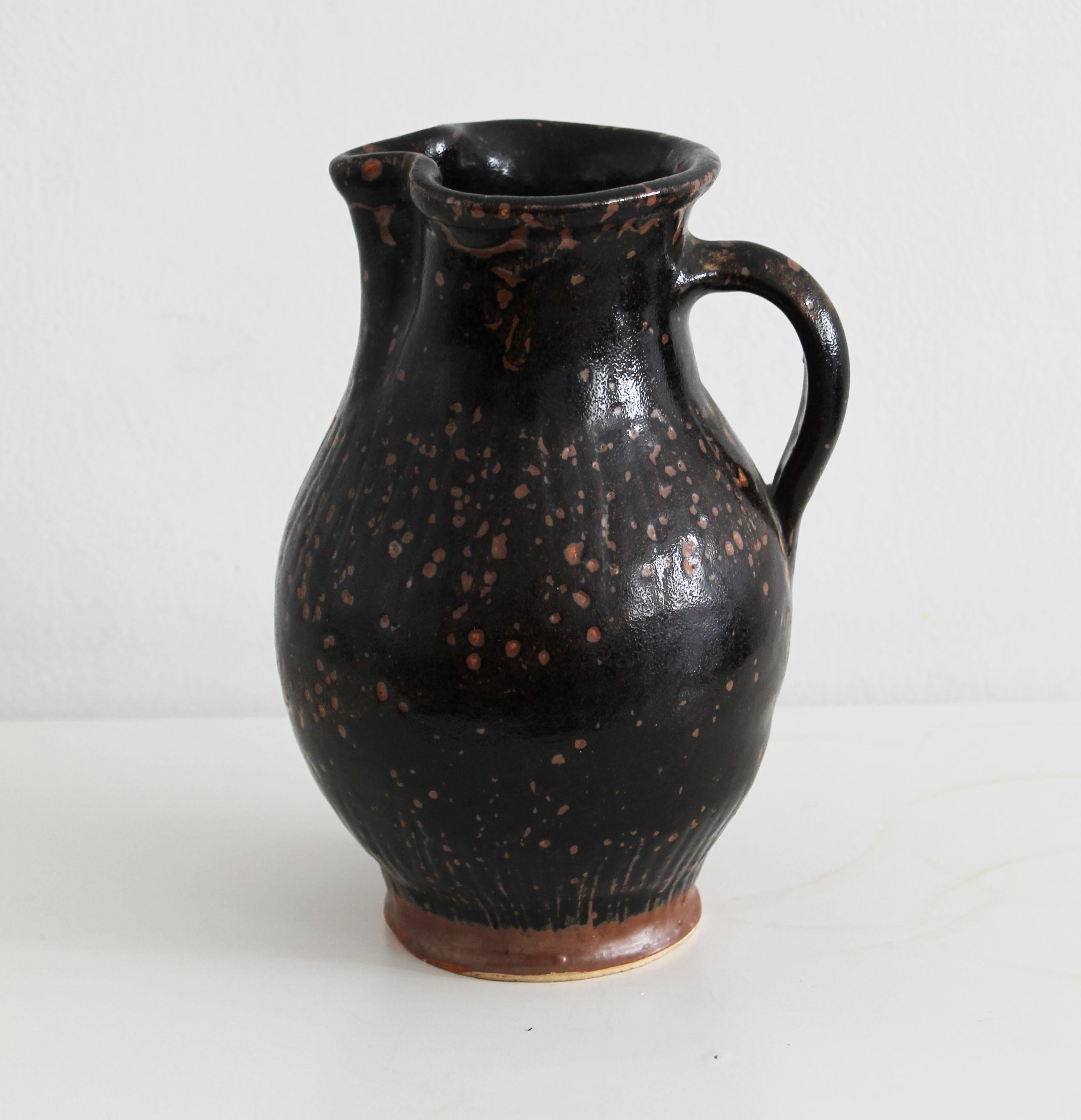 An original antique pitcher believed to be made at the end of 19th Century in the Austro-Hungarian Empire.

This piece is made of stoneware with a dark somewhat moody glaze. The jug has a wide, low-set handle, allowing the piece to be easily handled