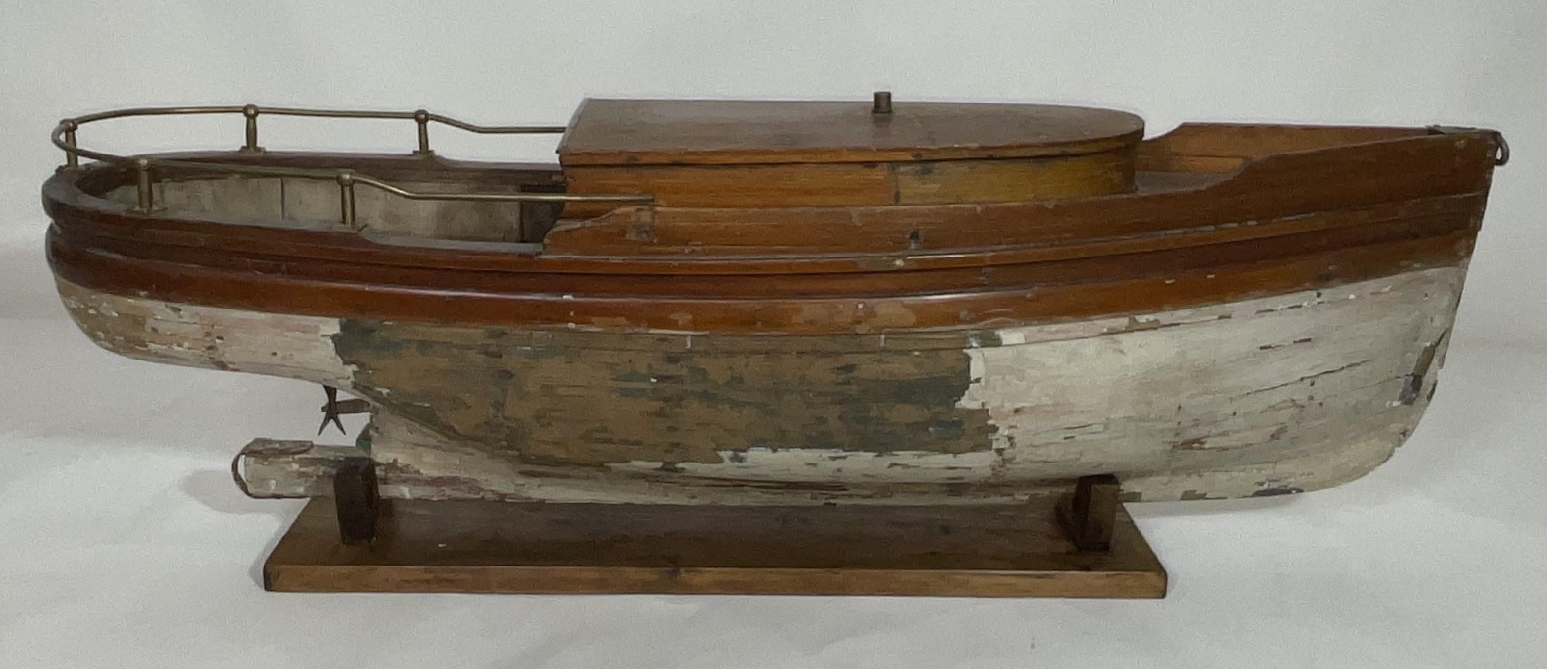Belle maquette de vedette ancienne avec coque et pont en planches. La coque est équipée d'une hélice. La lourde rambarde en laiton entoure la poupe. La base est plus récente. L : 36
