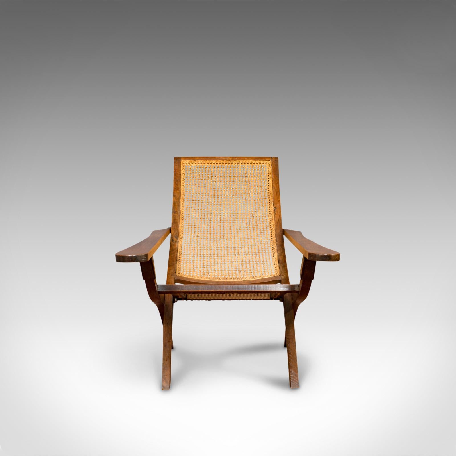 This is an antique plantation chair. An English, solid teak and bergere cane steamer-deck armchair, or garden lounger, dating to the Edwardian period of the early 20th century, circa 1910.

Of unusual, fold-away form
Displays a desirable aged