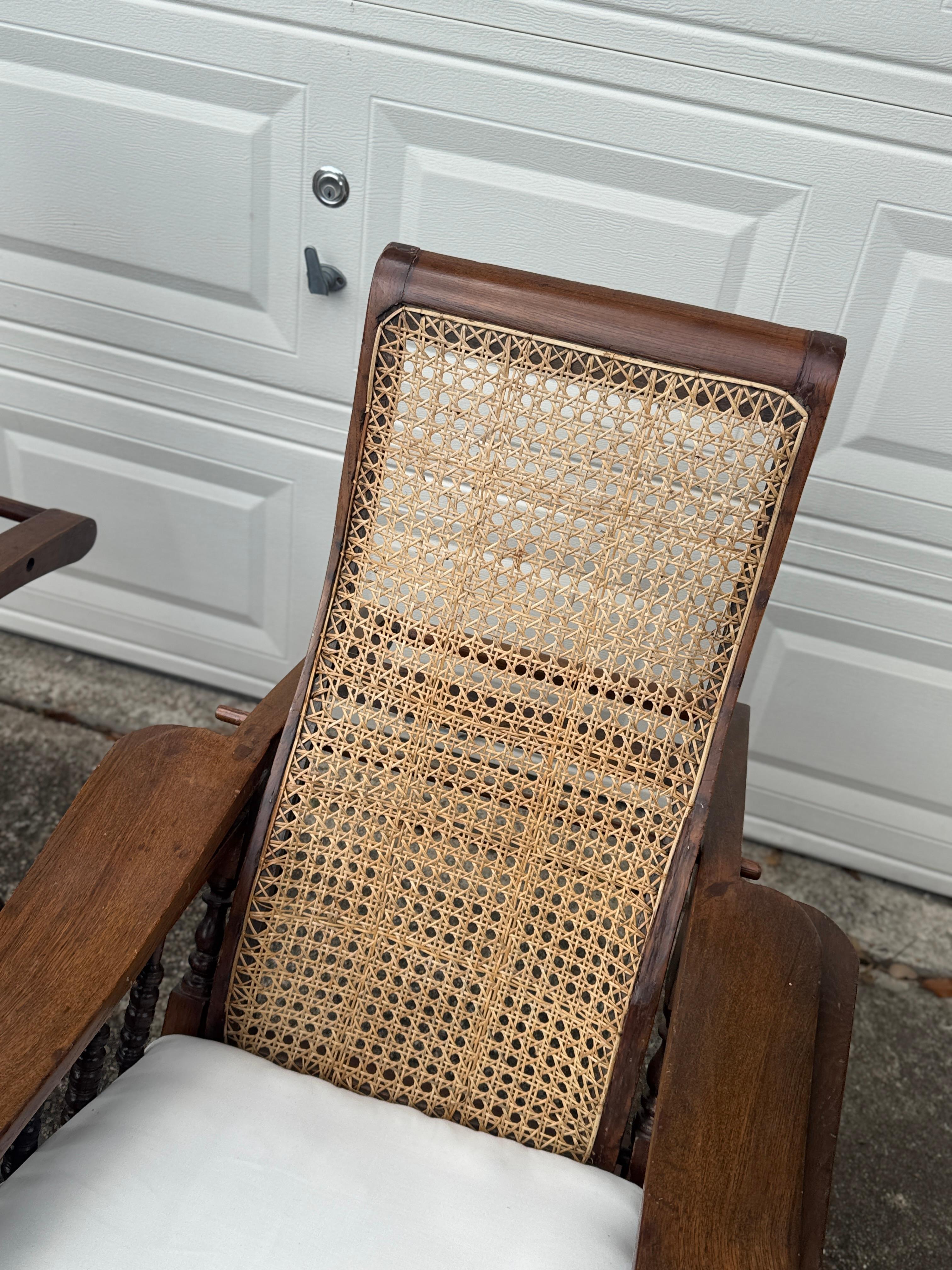 British Colonial Antique plantation chair with handwoven cane and fold out footrests, circa 1920S For Sale