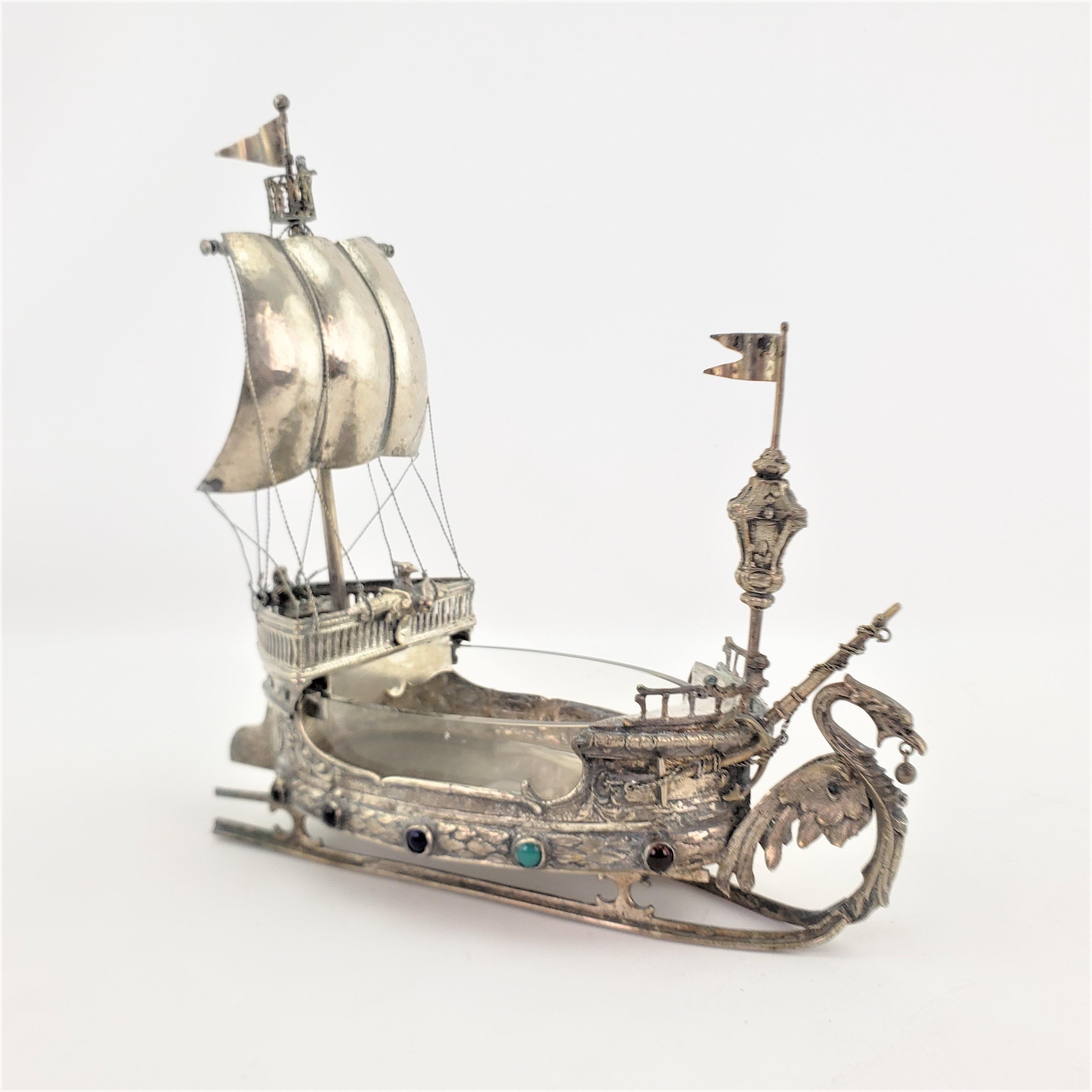 This antique nef was made by an unknown maker and originated from Germany from approximately 1900 in a Spanish Colonial style. The ship or galleon is composed of metal which has been nickel silver plated, to give the appearance of silver and is