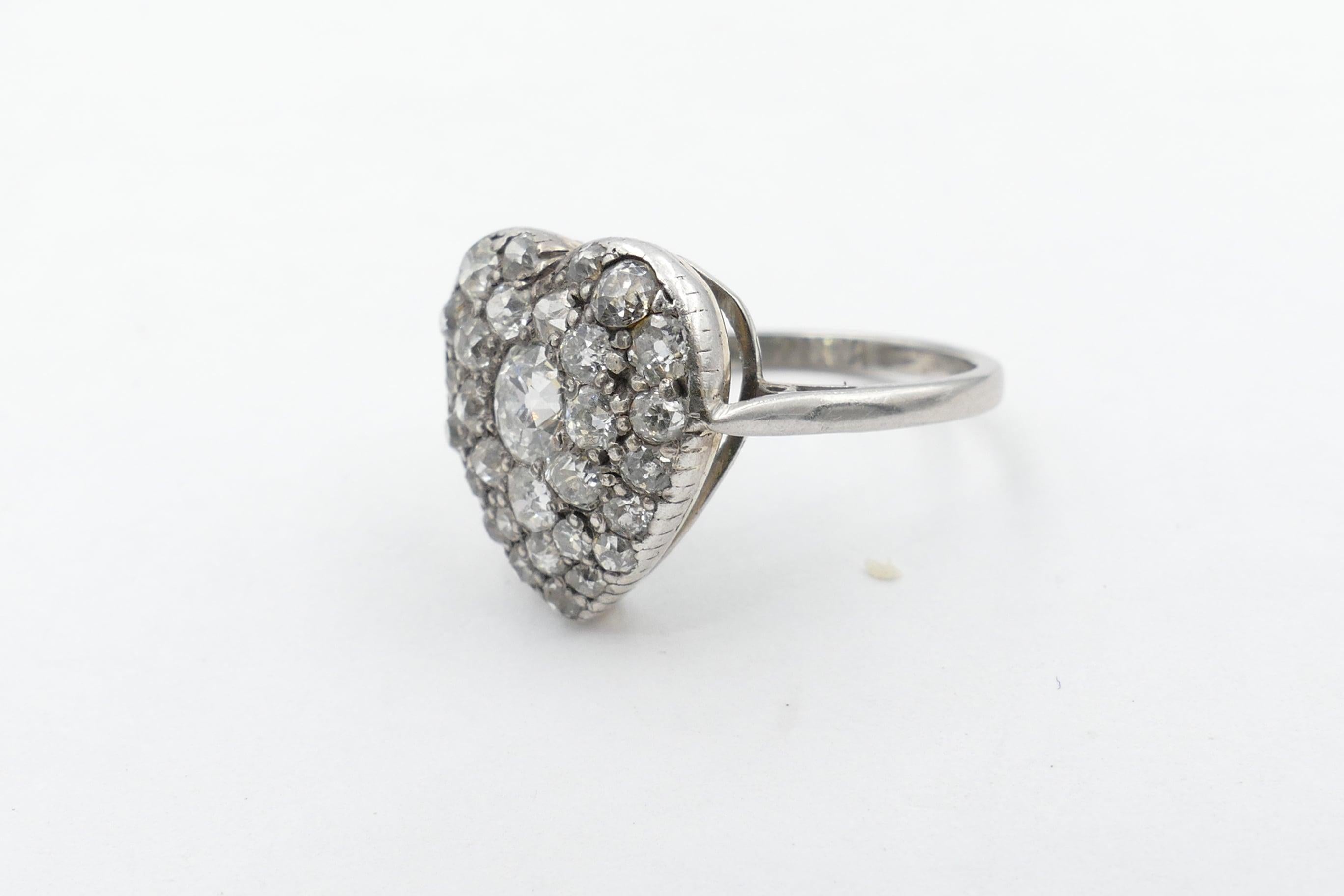 The Centrepiece of this beautiful Antique Heart Shaped Diamond Ring is one Old EuropeanCut Diamond 4.10 X 4.28 X 2.86mm, Colour G, Clarity SI1. It is surrounded by 6 Old European Single Cut Diamonds, Colour G/I & Clarity SI1-I1 & Bead Set.
The Band